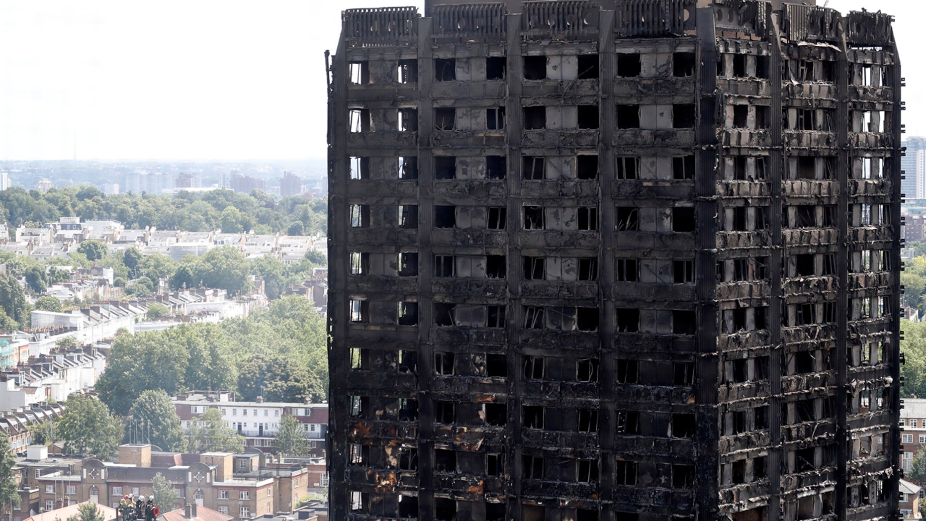 Firemen, left, inspect the scorched facade of the Grenfell Tower in London, Thursday, June 15, 2017, after a massive fire raced through the 24-storey high-rise apartment building in west London early Wednesday. Firefighters are beginning the task of combing through the devastated apartment tower, checking integrity of the structure and searching to find victims.(AP Photo/Frank Augstein)