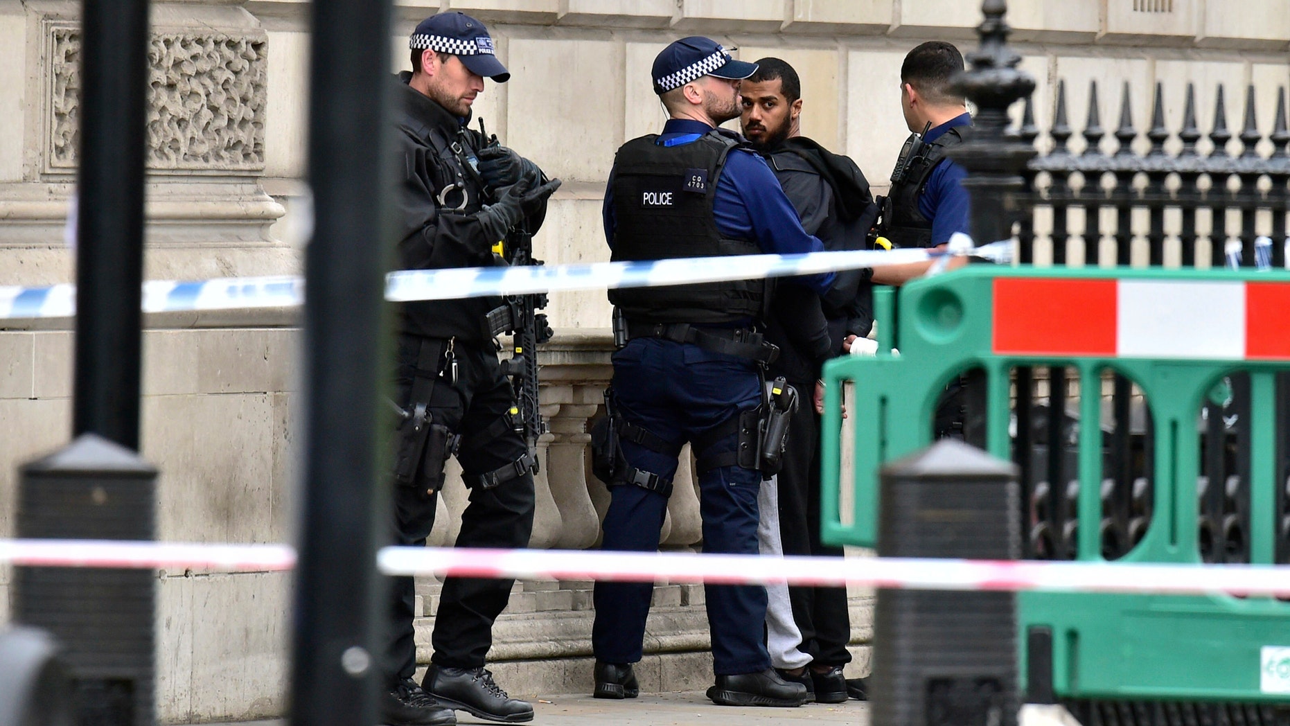 Armed police talk to man at the scene after a person was arrested following an incident in Whitehall in London, Thursday April 27, 2017. London police arrested a man for possession of weapons Thursday near Britain's Houses of Parliament. (Dominic Lipinski/PA via AP)