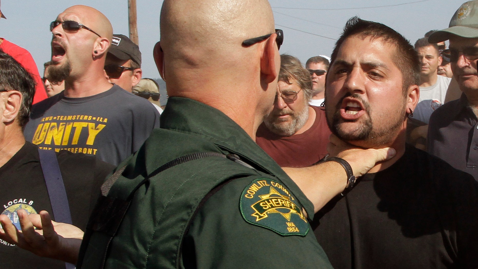 A Cowlitz County Sheriff grabs a union worker by the throat as police move in on several hundred union workers blocking a grain train in Longview, Wash., Wednesday, Sept. 7, 2011.