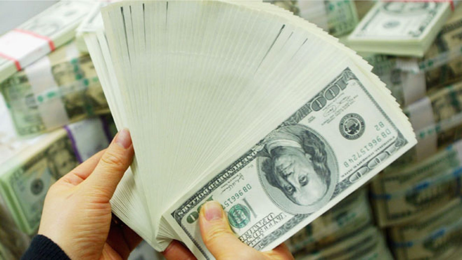 SEOUL, SOUTH KOREA - FEBRUARY 22: A South Korean banker carries US dollar bank notes at the Korea Exchange bank on February 22, 2005 in Seoul, South Korea. The South Korean won jumped to its highest intraday level in more than seven years in domestic trade on Tuesday, boosted by strong foreign equity buying and exporter deals. (Photo by Chung Sung-Jun/Getty Images)