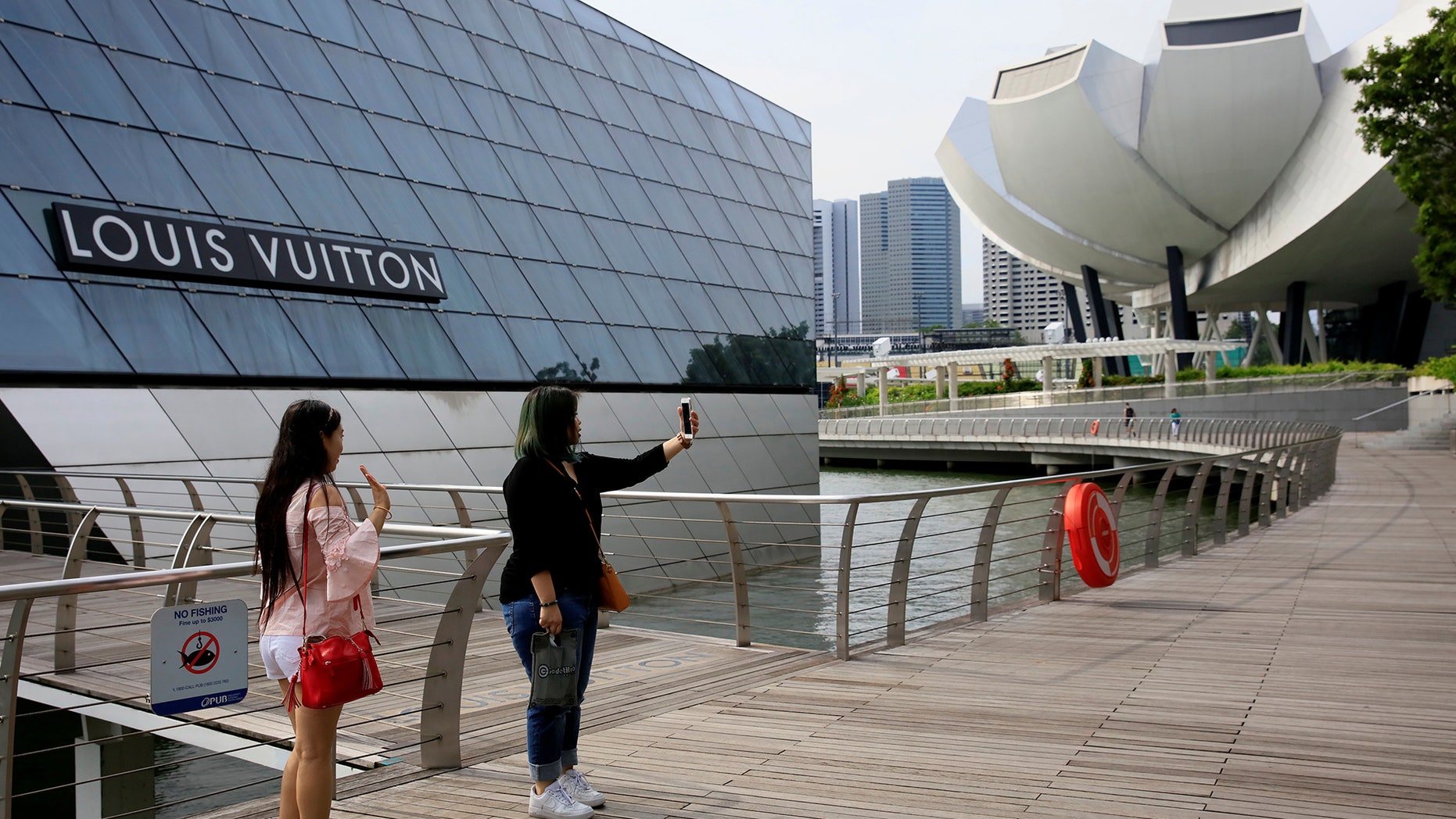 Shoppers take selfies in front of a Louis Vuitton shop in Singapore May 19, 2017.