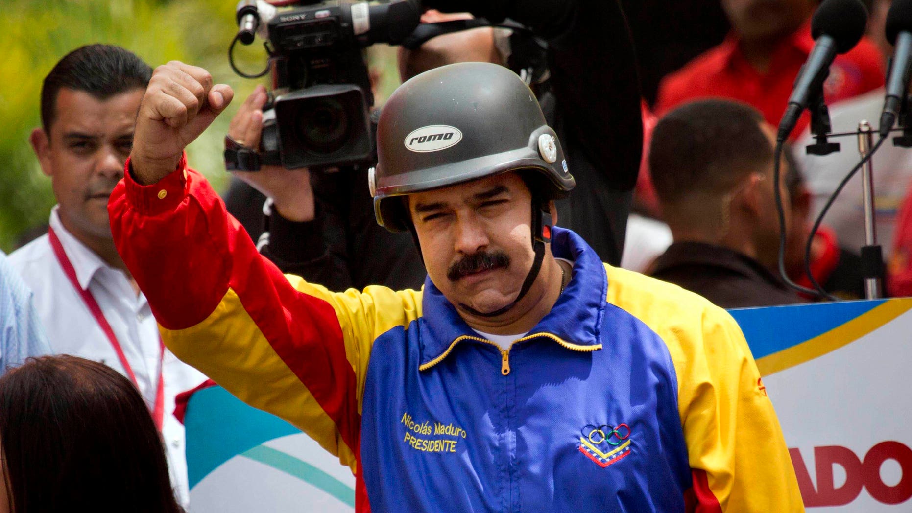 A helmet wearing Venezuelan President Nicolas Maduro cheers motorcyclists during a rally in support of his government in Caracas, Venezuela, Monday, Feb. 24, 2014. Since Feb. 12, opponents of President Nicolas Maduro have been staging countrywide protests that the government says have resulted in scores of deaths and more than more than a hundred injured. The demonstrators blame Maduro's administration for the country's high crime rate and economic troubles. (AP Photo/Rodrigo Abd)