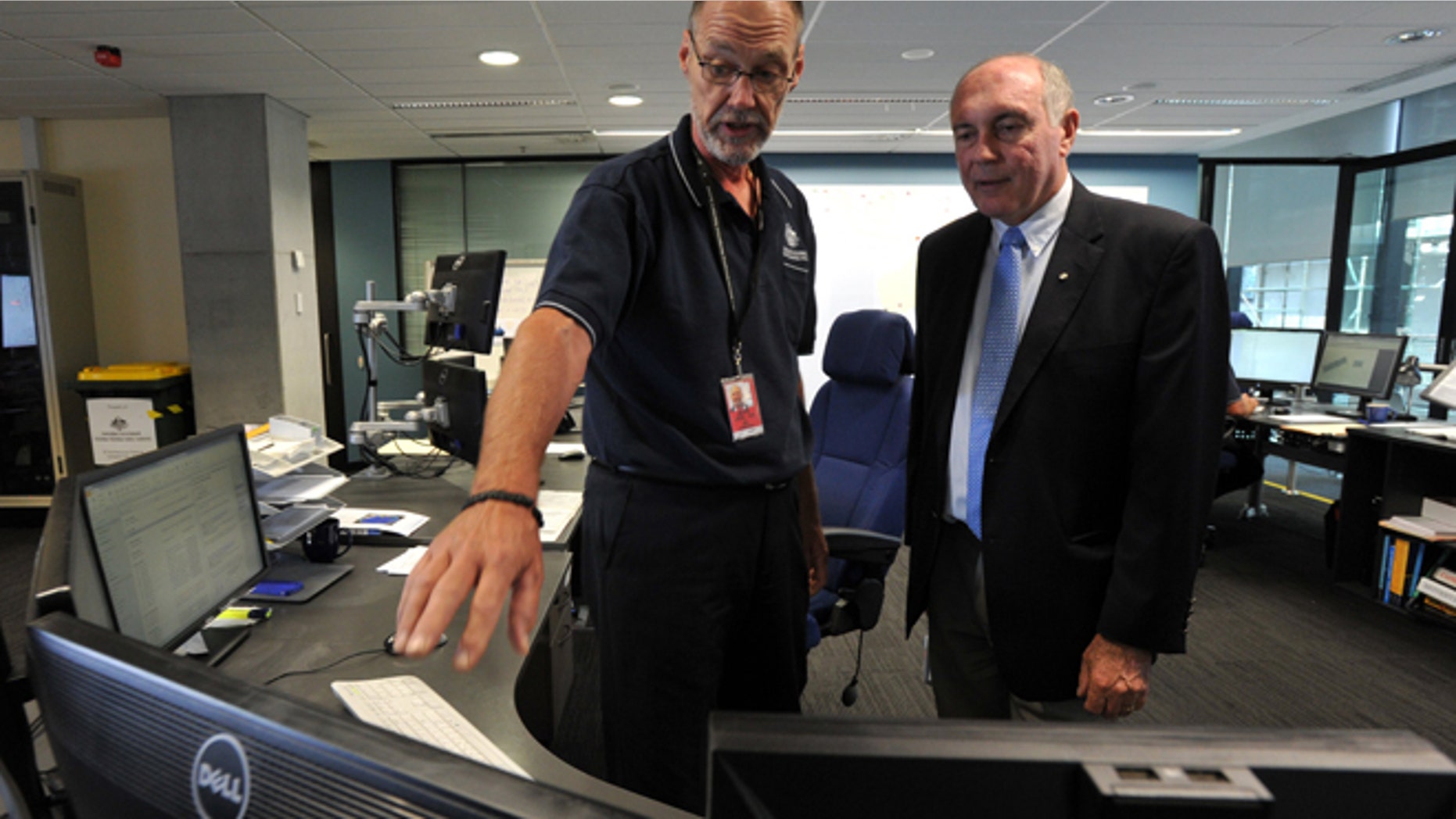 In this March 23, 2014 photo, Australian Deputy Prime Minister Warren Truss, right, talks with John Rice, senior search and rescue officer and mission coordinator for the search for the missing Malaysia Airlines Flight MH370, at rescue coordination center of the Australian Maritime Safety Authority in Canberra. Just weeks before the hunt for the missing Malaysian airliner is set to resume, an Australian official said Thursday, Aug. 28, that the sprawling search area in the southern Indian Ocean may be extended farther south based on a new analysis of a failed attempt to call the plane by satellite phone.