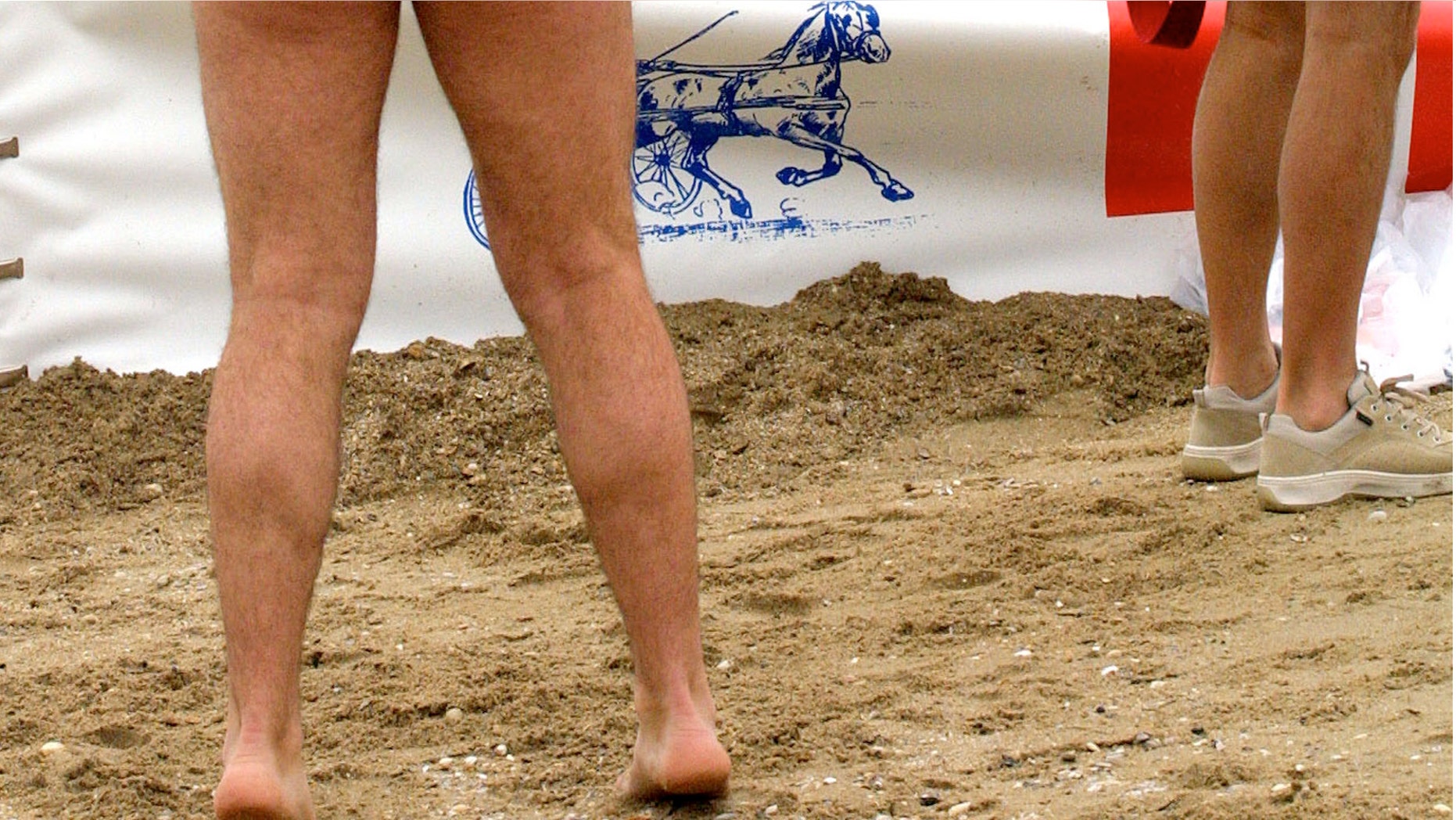 391578 08: A participant in the First European Bare Bottom Run plays with his dog as others prepare for the event July 8, 2001 in Zanvoort, The Netherlands. Some 100 people of all sizes and shapes joined the five kilometer (three mile) fun run which is already popular in San Francisco and Australia. (Photo by Michel Porro/Getty Images)