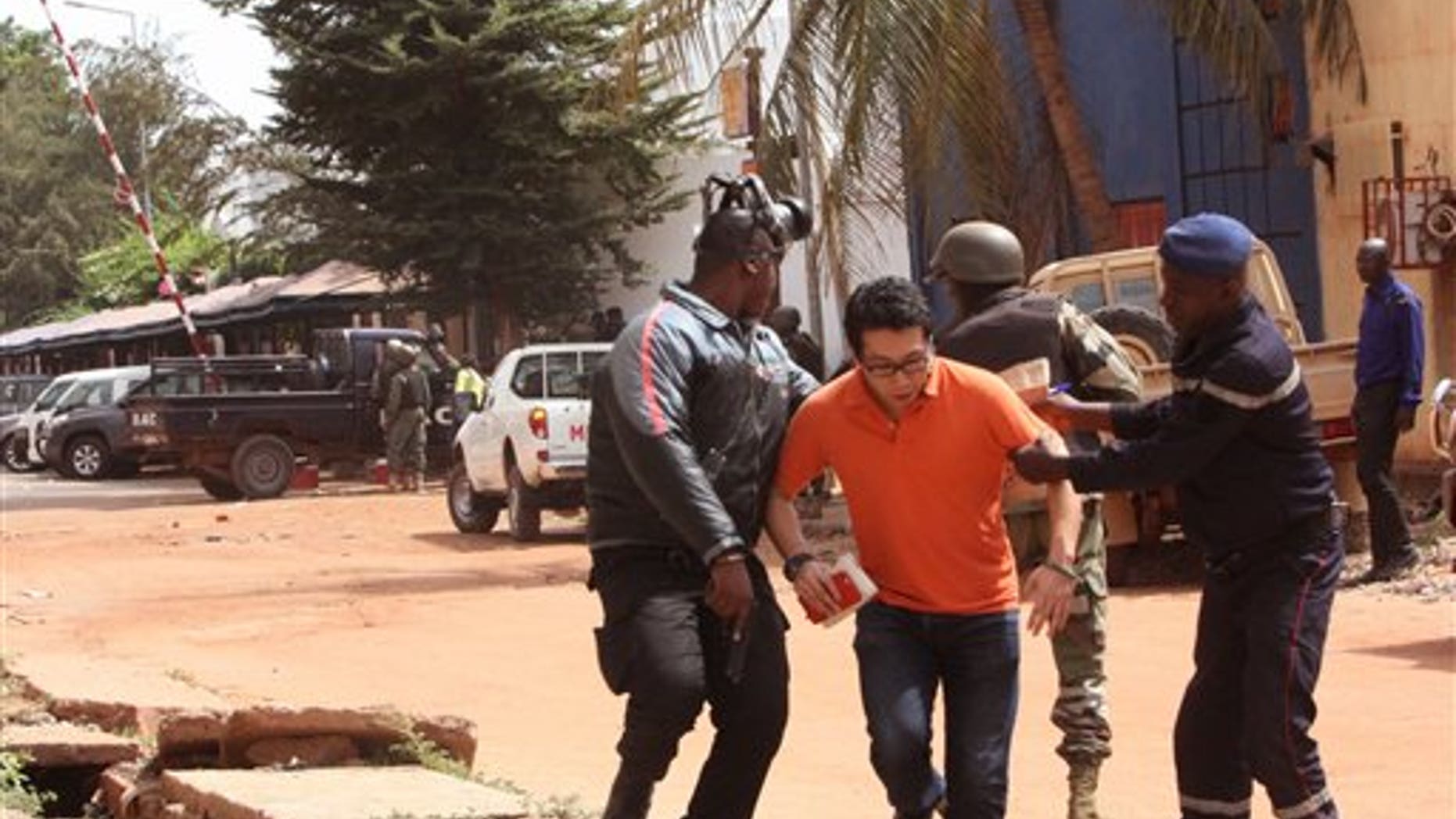Mali trooper assist a hostage, centre, to leave the scene, from the Radisson Blu hotel to safety after gunmen attacked the hotel in Bamako, Mali, Friday, Nov. 20, 2015. Islamic extremists armed with guns and throwing grenades stormed the Radisson Blu hotel in Mali's capital Friday morning, killing at least three people and initially taking numerous hostages, authorities said. (AP Photo/Harouna Traore)