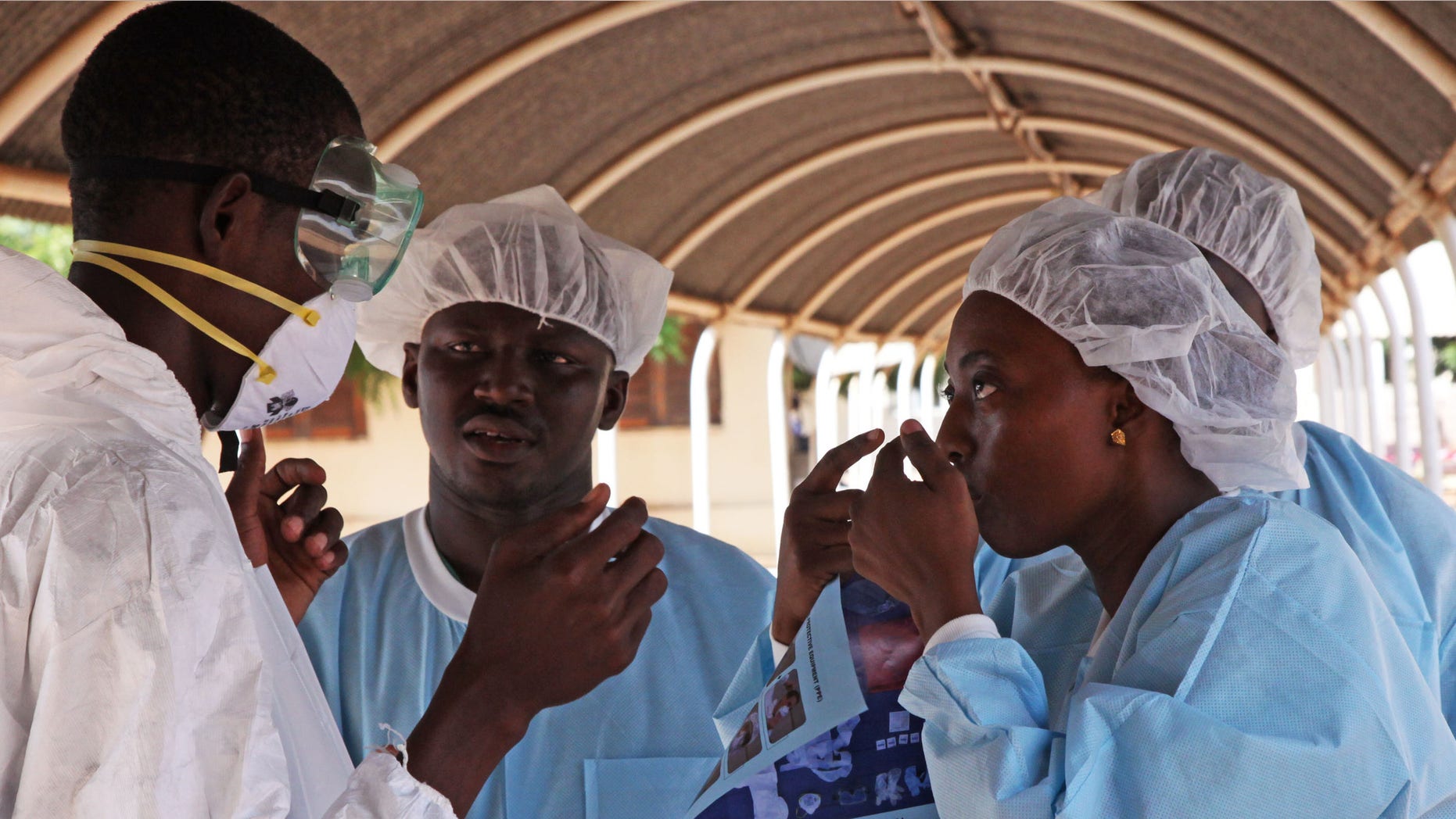 Oct. 25, 2014: A health worker, right, briefs another, left, on the use of their Ebola security gear before working with diseased Fanta Kone at a Ebola virus center in Kayes, Mali