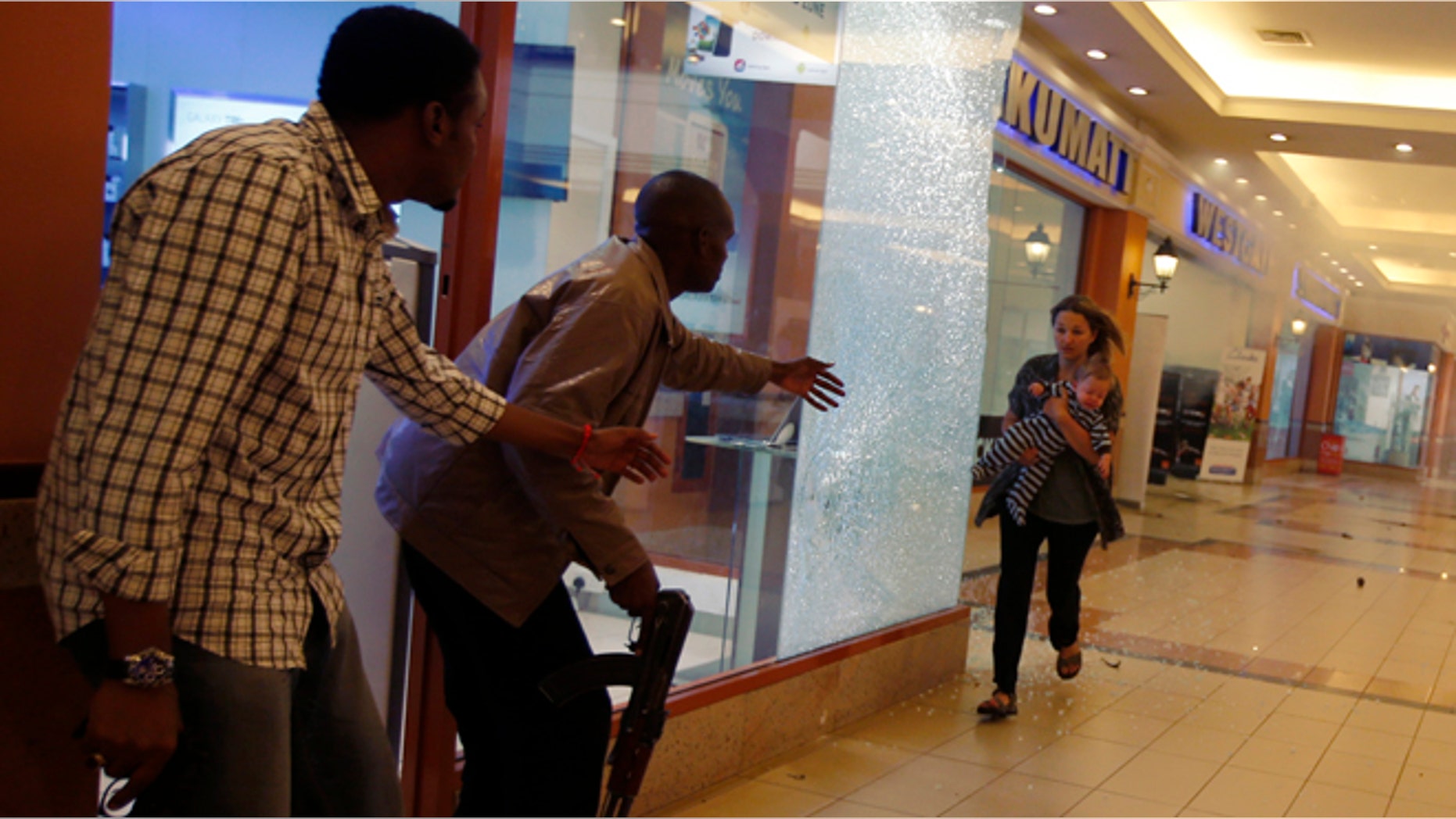 Armed police guide a woman carrying a child to safety as they hunt gunmen who went on a shooting spree at Westgate shopping centre in Nairobi, September 21, 2013.