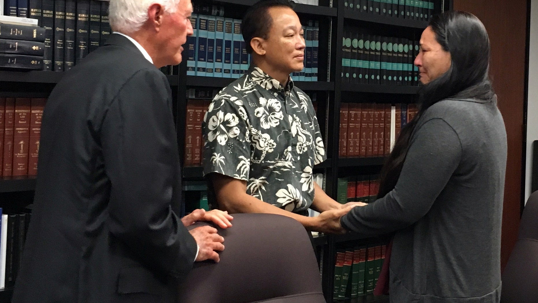 Keith Lee, center, a lawyer representing the Waianae Coast Health Center, holds hands with Rachel Marrero as her attorney Richard Fried looks on at a news conference in Honolulu, Wednesday, Sept. 14, 2016. The federal government is settling her malpractice lawsuit for $4.2 million after her husband went to the Waianae Coast Comprehensive Health Center with a sore throat and ended up dead. (AP Photo/Jennifer Sinco)