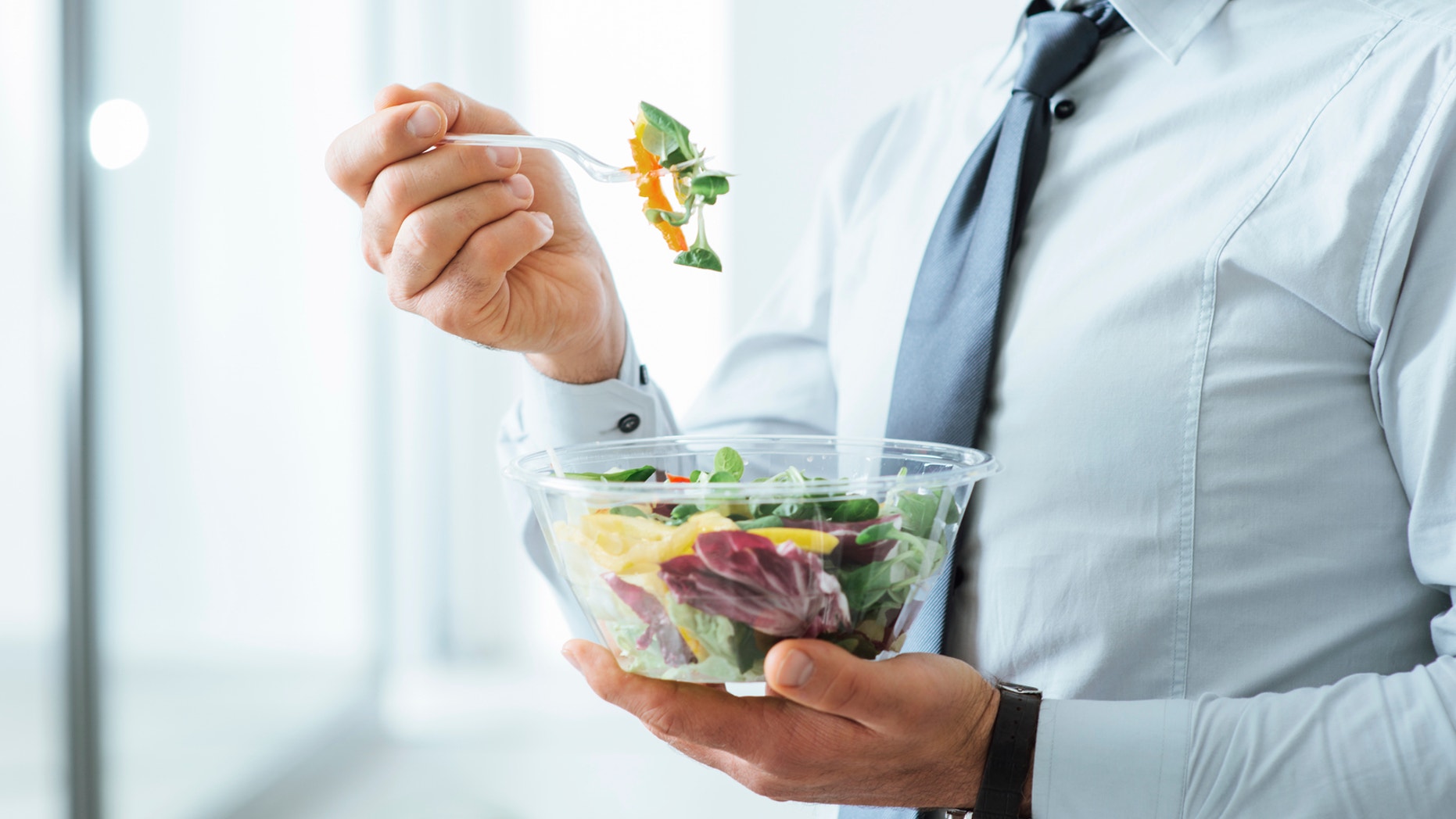 Businessman having a vegetables salad for lunch, healthy eating and lifestyle concept, unrecognizable person