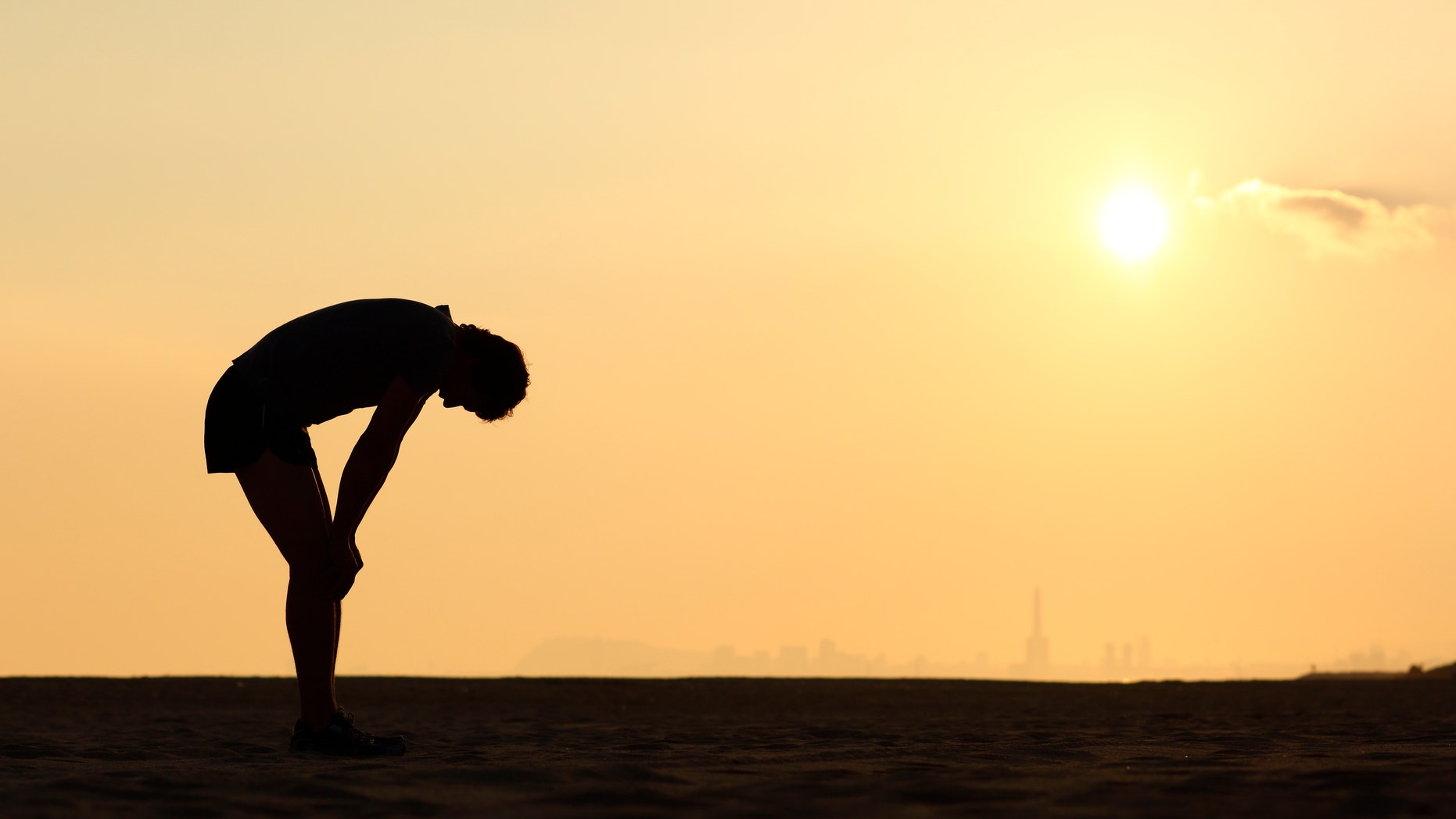Silhouette of an exhausted sportsman at sunset with the horizon in the background