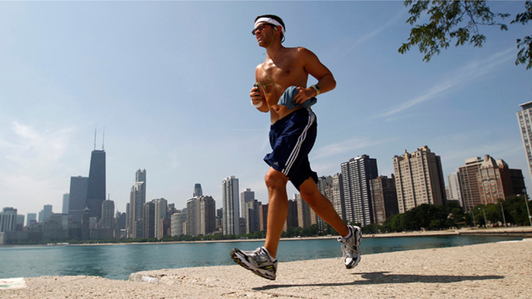 A man runs along the water near North Avenue Beach in Chicago July 20, 2011. The heat index is expected to exceed 110 degrees Fahrenheit or 43 degrees Celsius. REUTERS/Jim Young (UNITED STATES - Tags: ENVIRONMENT)