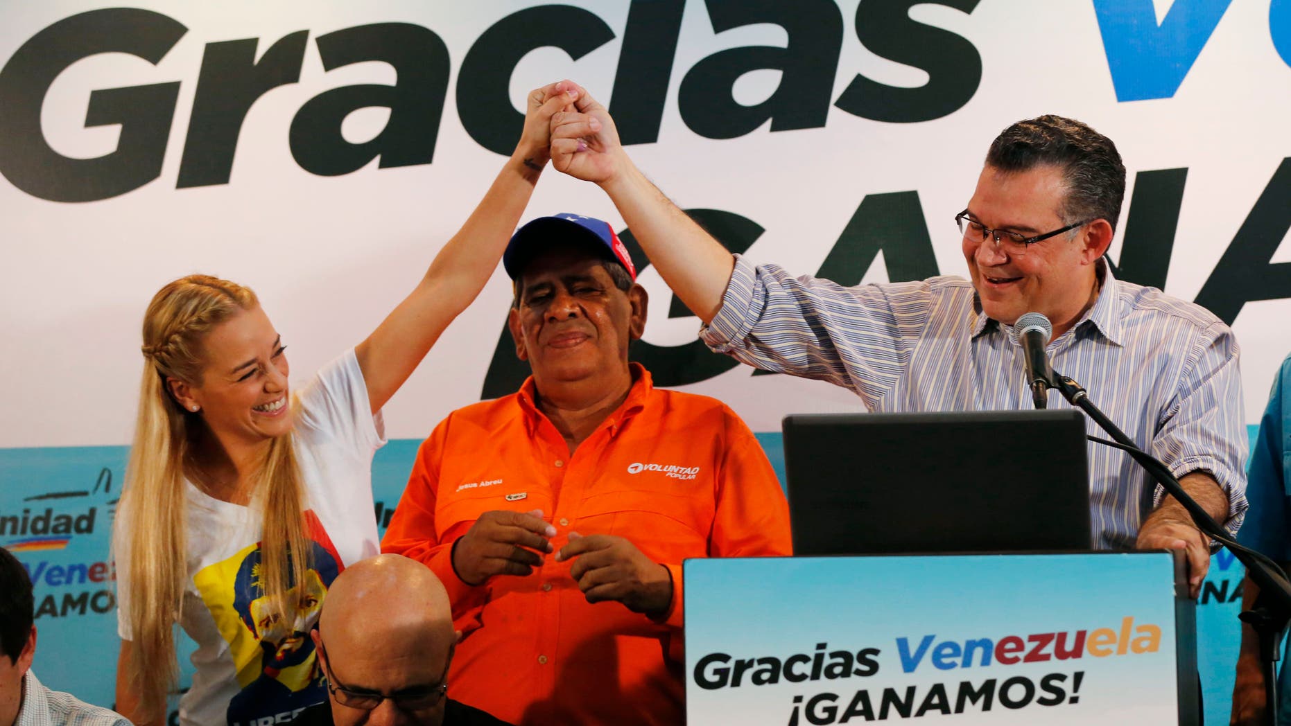 Lilian Tintori, esposa del encarcelado líder opositor Leopoldo López, izquierda, sostiene la mano del reelecto legislador Enrique Márquez, del estado Zulia, durante una rueda de prensa en Caracas, Venezuela, el lunes 7 de diciembre de 2015. La oposición venezolana ganó el control de la Asamblea Nacional en las elecciones del domingo 6 de diciembre. (AP Photo/Ariana Cubillos)