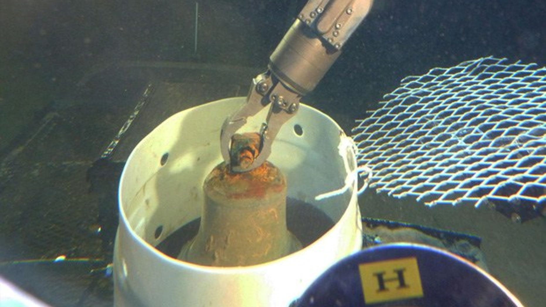 Manipulator arm of HURL’s submersible places the I-400 bell into a collection basket. (HURL/UH)