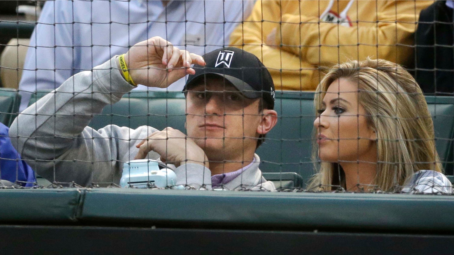 April 14, 2015: Johnny Manziel, left, sits with Colleen Crowley during a baseball game between the Los Angeles Angels and the Texas Rangers in Arlington, Texas. Dallas police announced Friday they were launching a criminal investigation into a domestic violence assault complaint filed against Manziel, who was involved in an altercation last weekend during which he allegedly struck Crowley several times. (AP Photo/LM Otero)