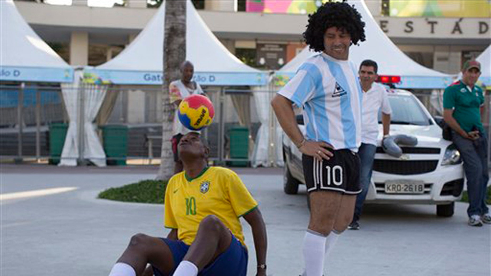 CORRECTING MARADONA ON THE RIGTH - The street performing mime, Daniel Gonzalez, righ, who is dressed to resemble Argentine soccer great Diego Armando Maradona, looks back at Marcio Pereira, dressed up as Brazilian soccer great Pele as he controlls the ball in front of Maracana stadium, Rio de Janeiro, Brazil, Wednesday, June 11, 2014. The World Cup soccer tournament starts Thursday. (AP Photo/Leo Correa)