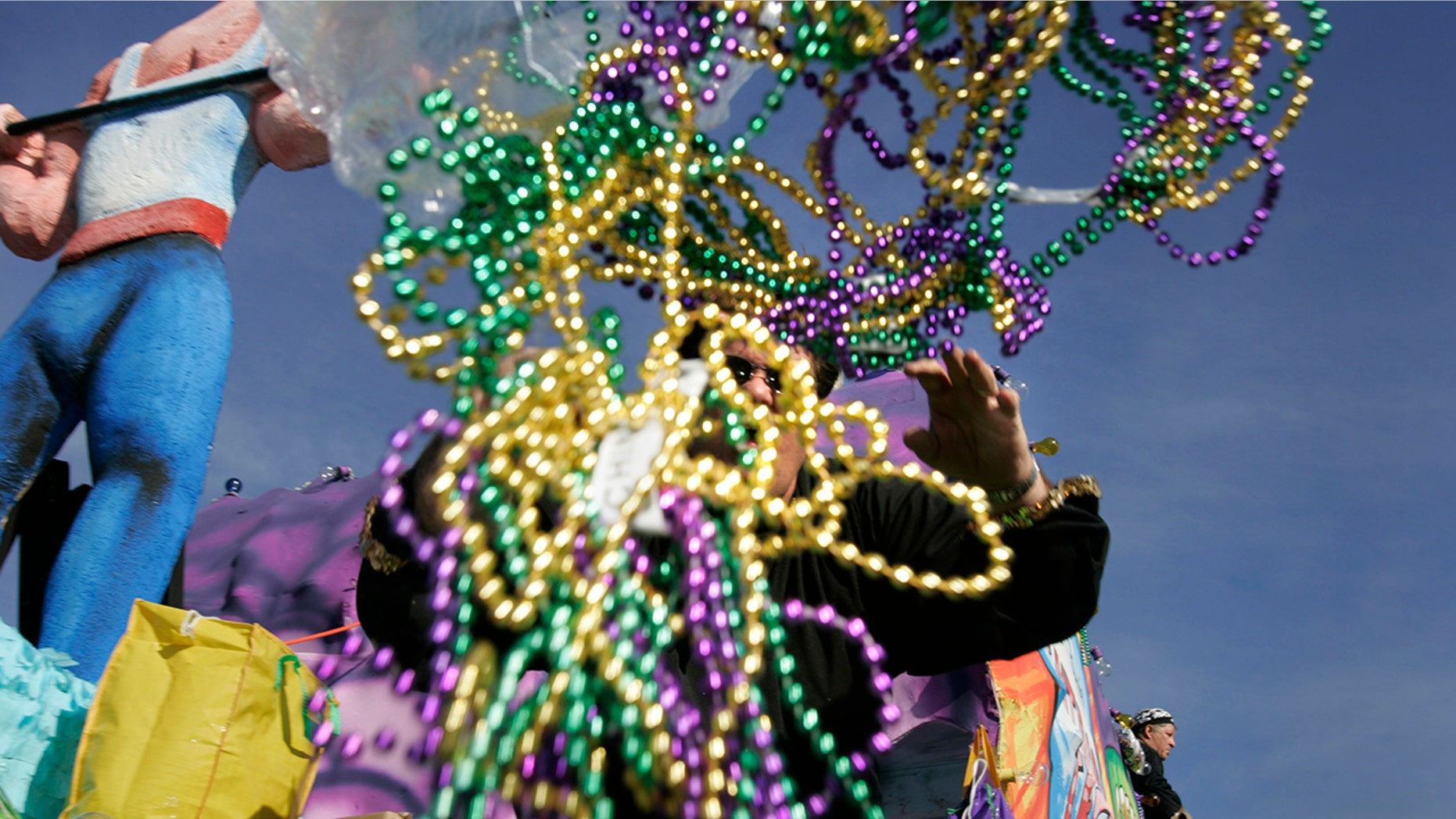 A parade rider throws out handfuls of beads during a Mardi Gras parade.