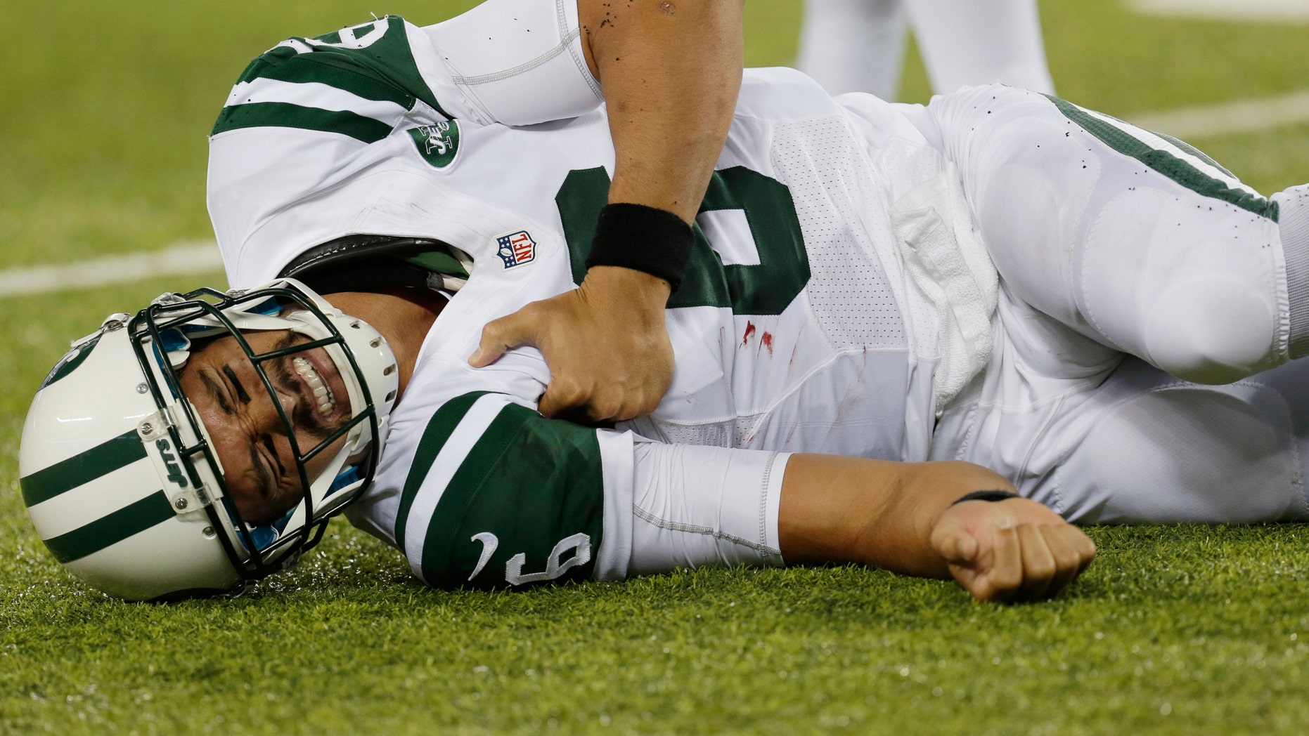 New York Jets quarterback Mark Sanchez (6) reacts to an injury during the second half of a preseason NFL football game against the New York Giants, Saturday, Aug. 24, 2013, in East Rutherford, N.J. He left the game with what appeared to be a shoulder injury. (AP Photo/Julio Cortez)