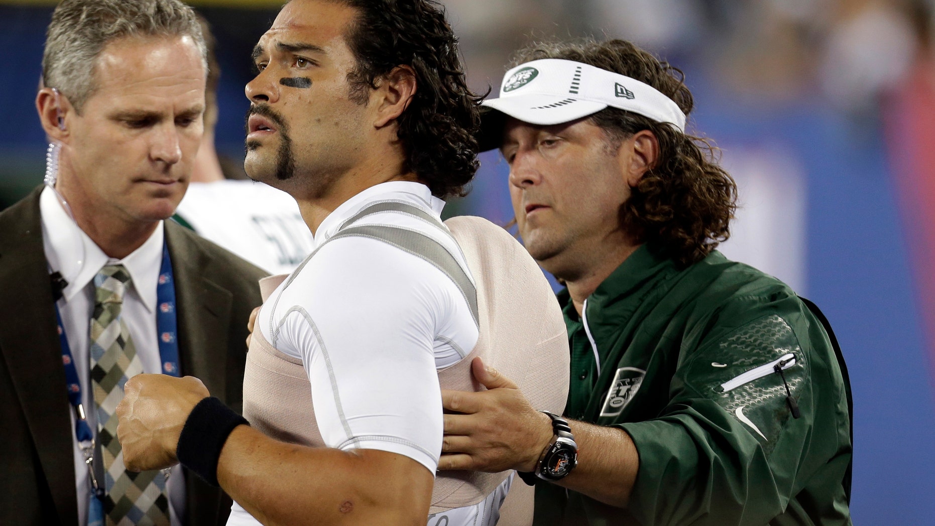 A trainer wraps New York Jets quarterback Mark Sanchez, center, during the second half of a preseason NFL football game against the New York Giants, Saturday, Aug. 24, 2013, in East Rutherford, N.J. (AP Photo/Julio Cortez)