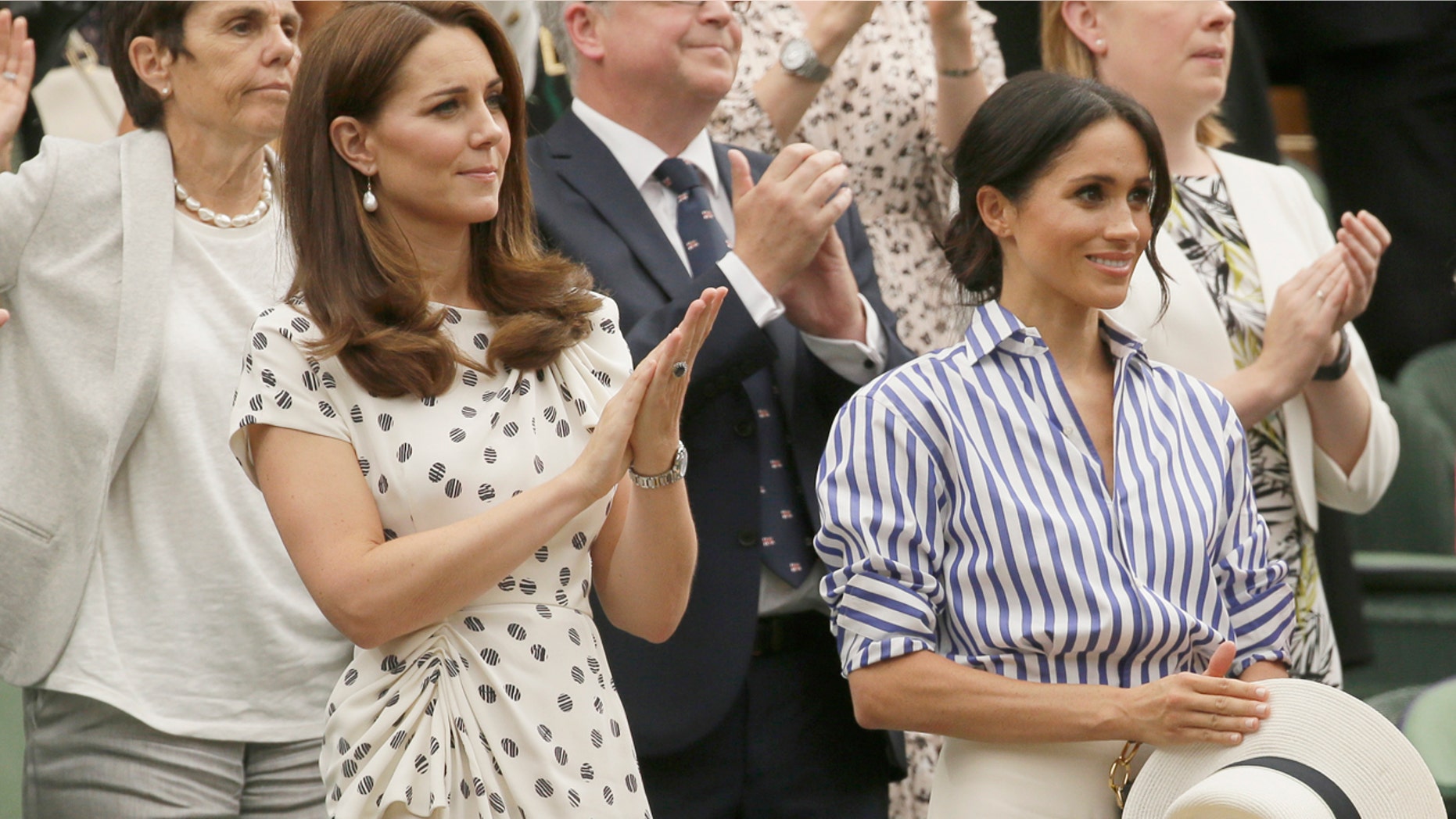 Duchess Kate Middleton and Meghan Markle watch the women's Wimbledon finale while Markle clings onto her straw hat she was unable to wear in the royal box on Saturday.