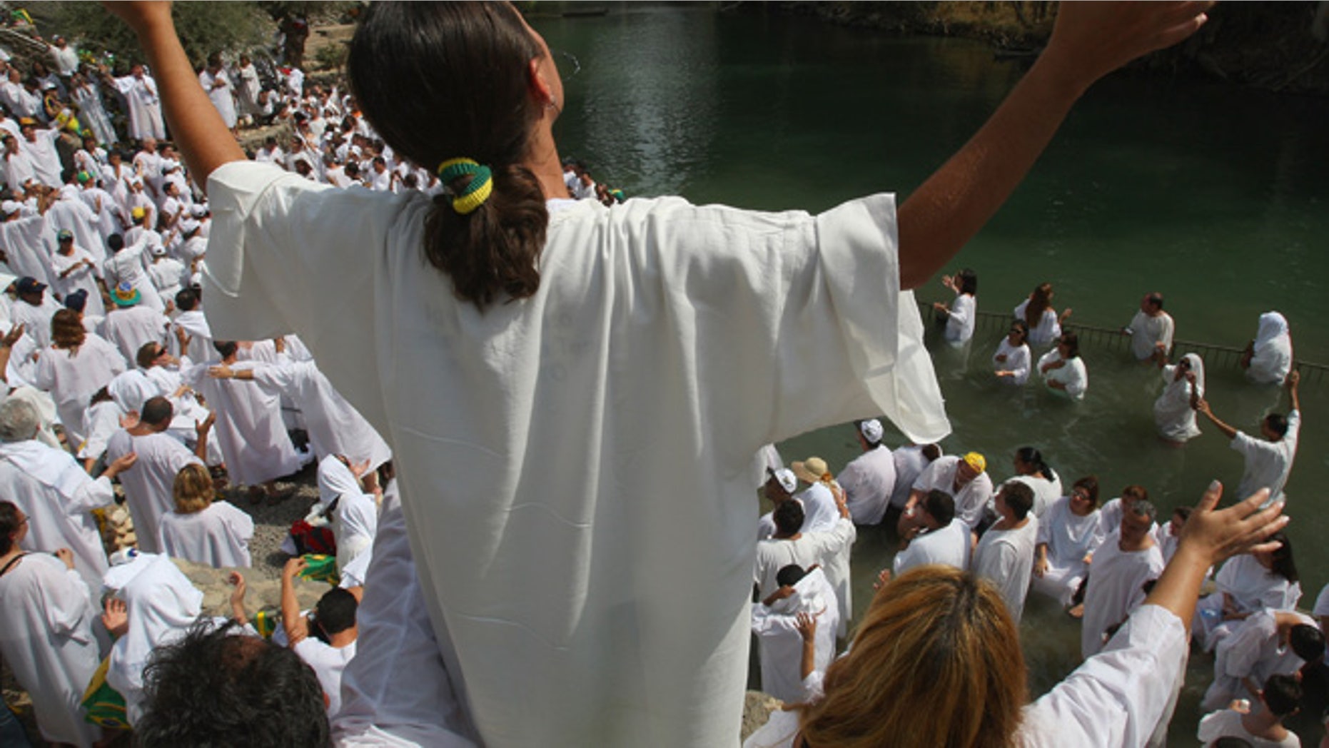 YARDENIT, ISRAEL - OCTOBER 01: Brazilian Evangelist Christians raise their arms in prayer during their mass baptism ceremony in the Jordan River on October 1, 2007 at Yardenit in northern Israel. The group of 700 worshippers descended in the biblical river as part of their pilgrimage to the Holy Land. (Photo by David Silverman/Getty Images)