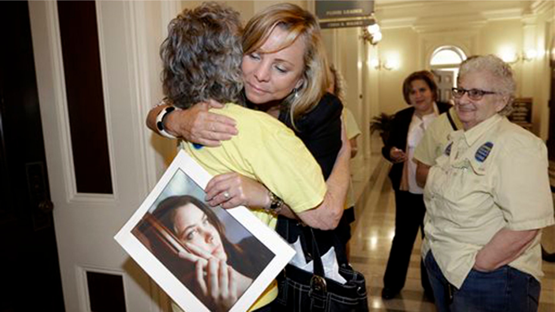 Sept. 9, 2015: Debbie Ziegler holds a photo of her daughter, Brittany Maynard, as she receives congratulations from Ellen Pontac, after a right-to die measure was approved by the state Assembly in Sacramento, Calif.