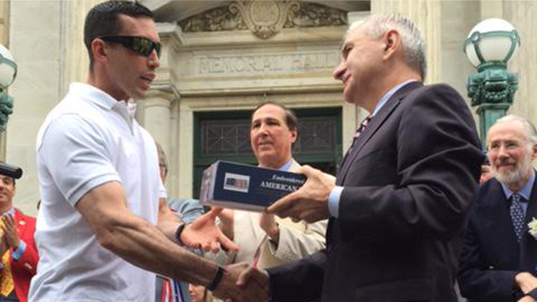 Green Beret P. Andrew McKenna, left, receives a flag that flew over the U.S. Capitol from Sen. Jack Reed (D-R.I.) at Bristol, R.I., Fourth of July parade. (Photo courtesy of Reed) .