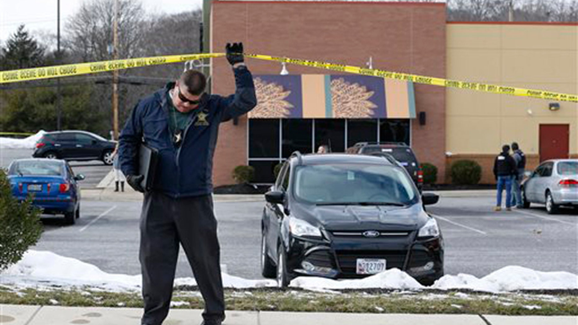 An investigator walks beneath a police tape line at the scene of a shooting at a shopping center in Abingdon, Md., Wednesday, Feb. 10, 2016. A man opened fire inside a shopping center restaurant during lunchtime. (AP Photo/Patrick Semansky)