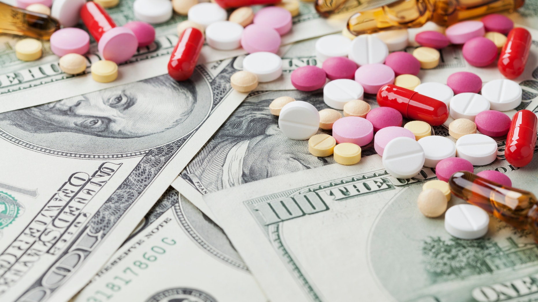 Heap of pharmaceutical drug and medicine pills scattered on dollar cash money, cost of medicinal product and treatment concept