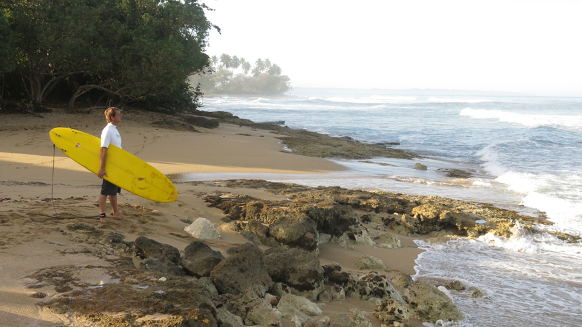 A surfer studies the waves at Wilderness Beach in Aguadilla, Puerto Rico.