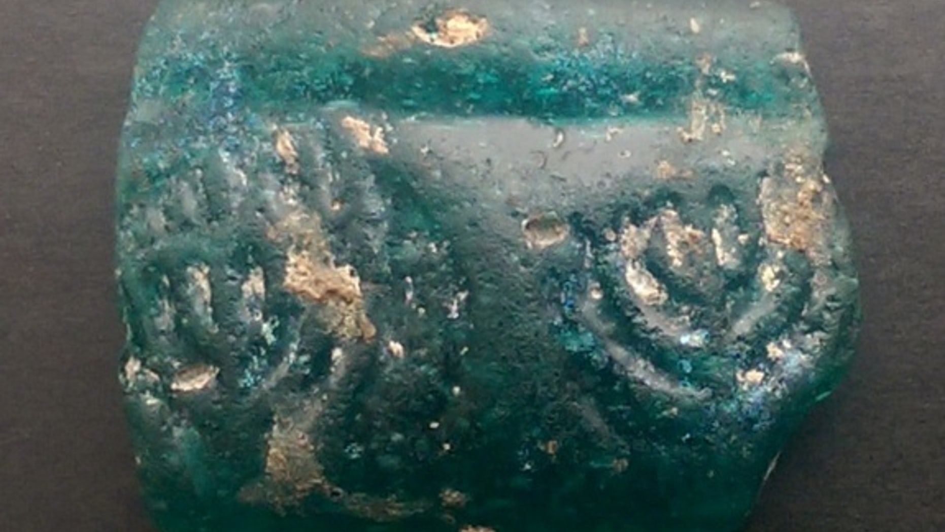 This glass fragment, embossed with two menorahs, was discovered by archaeologists in Israel on the second night of Hanukkah.