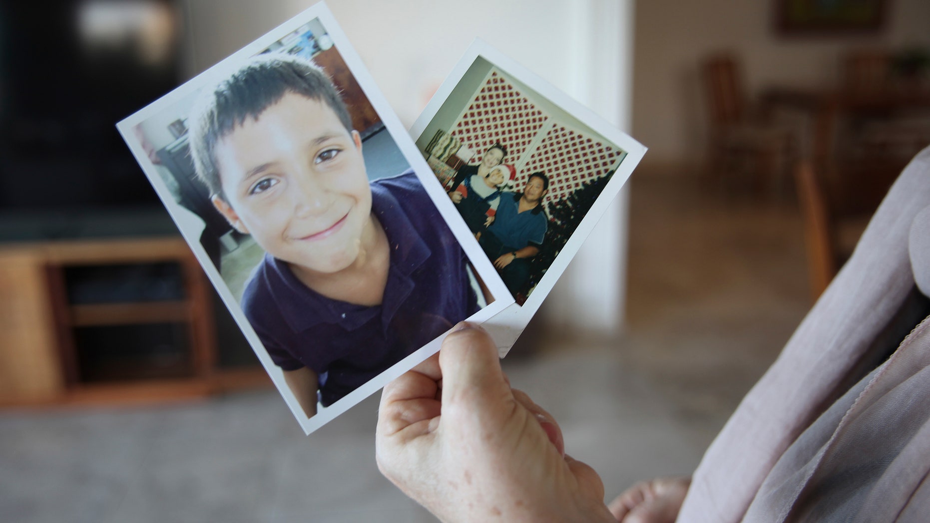 In this May 10, 2016, photo, Susan Callahan holds photos of her son Aron at her home in Honolulu. Her son is one of dozens of Hawaii teens who are sent out-of-state for treatment for mental illness because they can't find the proper treatment in the islands.