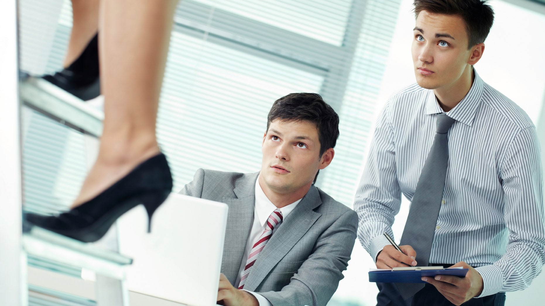 Two shocked managers looking at legs of their female colleague
