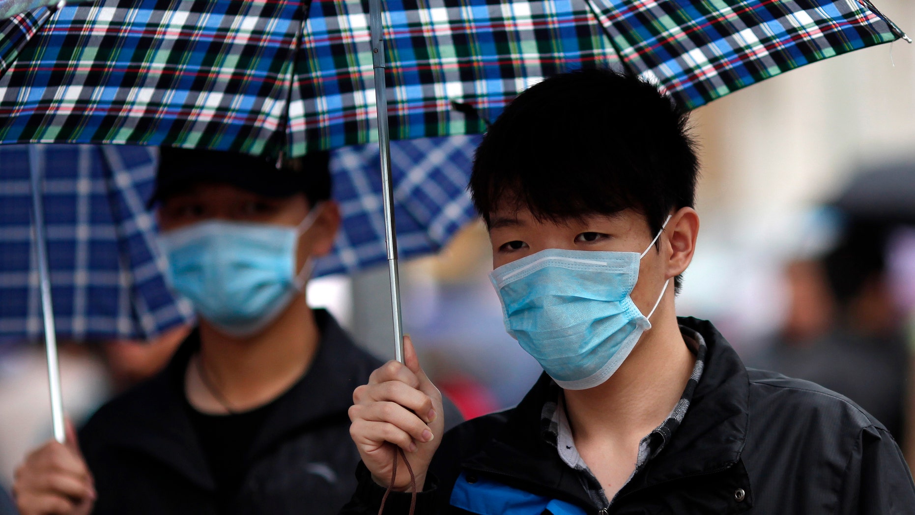 A man wears a face mask as he walks in a shopping area in downtown Shanghai April 5, 2013. REUTERS/Carlos Barria