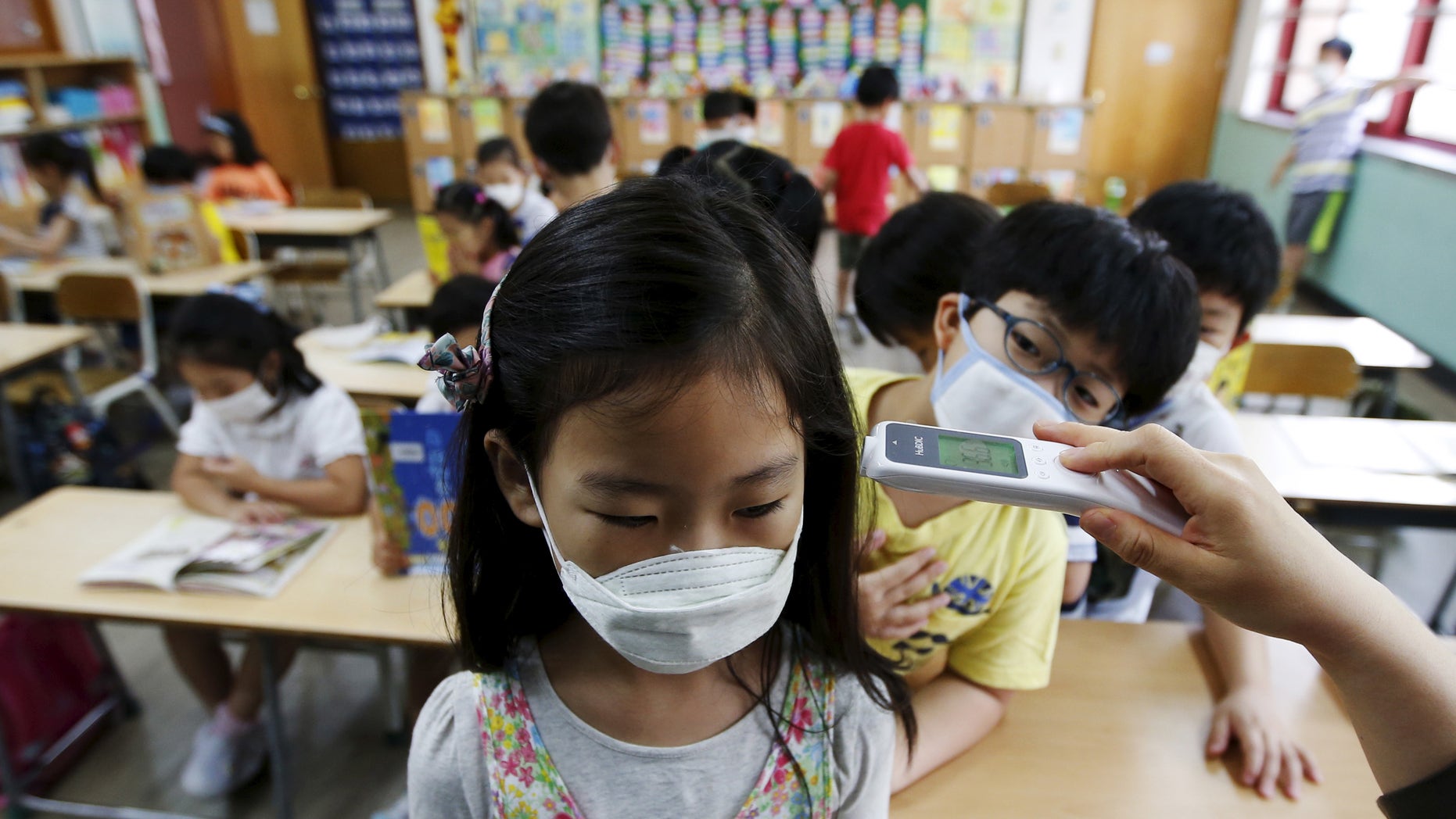 An elementary school student wearing a mask to prevent contracting Middle East Respiratory Syndrome (MERS), receives a temperature check at an elementary school in Seoul, South Korea, June 9, 2015. REUTERS/Kim Hong-Ji