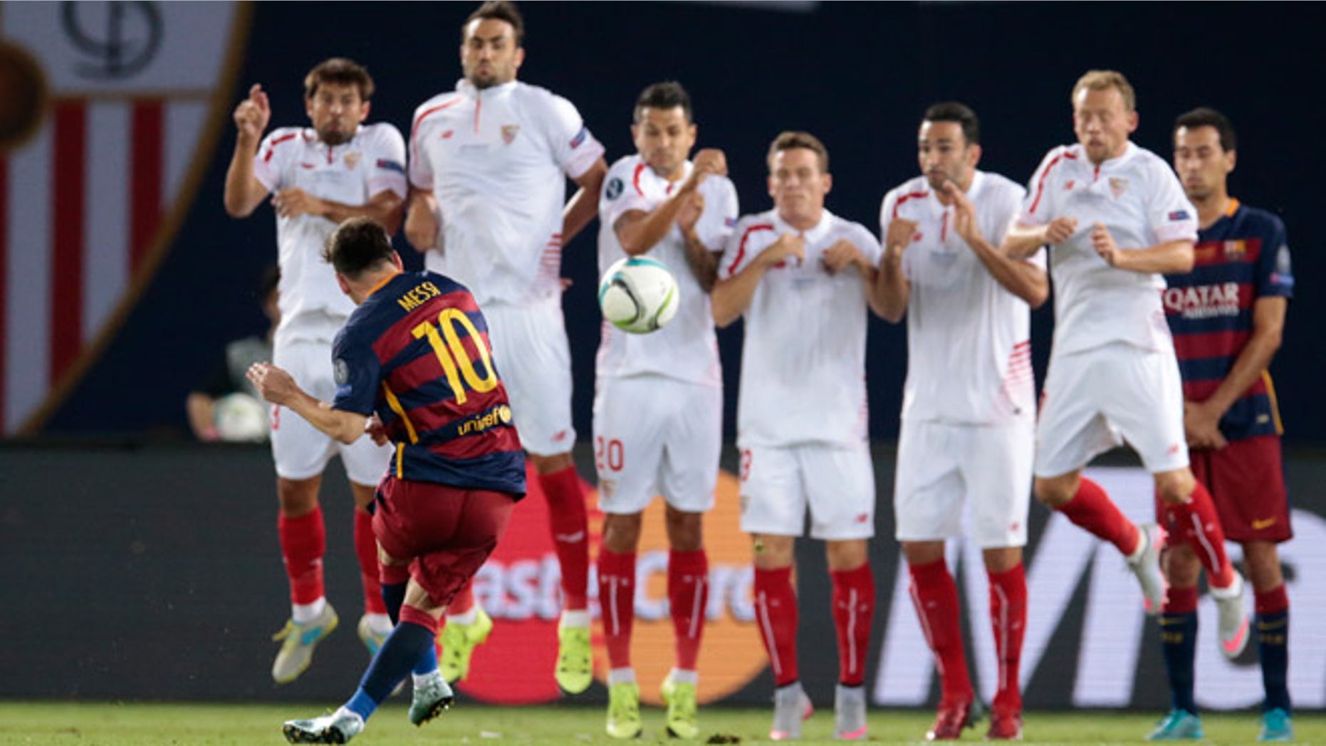 Barcelona's Lionel Messi, foreground, shoots a free kick to score his sideâs second goal during the UEFA Super Cup soccer match between FC Barcelona and Sevilla FC in Tbilisi, Georgia, on Wednesday, Aug. 12, 2015.