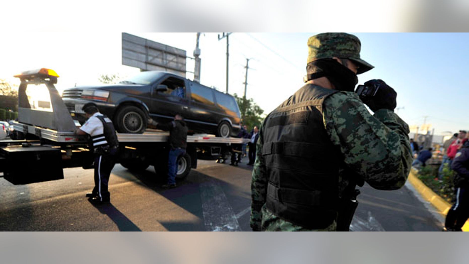 A soldier patrols as a vehicle that was discovered carrying bodies inside is taken away in Guadalajara, Mexico, Thursday Nov. 24, 2011. At least 20 bodies were discovered early Thursday in three vehicles abandoned in the heart of Guadalajara, Mexico's second-largest city and the site of the recent Pan American Games, according to an official with the prosecutor's office in the state of Jalisco. (AP Photo/Victor Fernandez)
