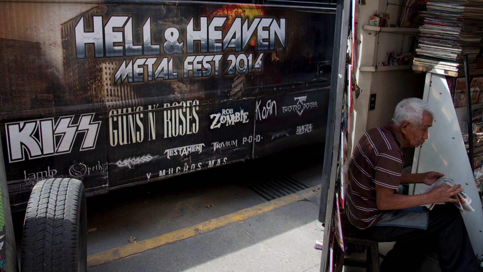 March 7, 2014. A man reads a newspaper next to publicity of "Hell and Heaven Metal Fest" concert, posted on bus in Mexico City. The Mexico state government canceled the concert saying the March 15-16 "Hell and Heaven Metal Fest" planned for a fairground just east of Mexico City did not have adequate safety plans, posing a risk to concert-goers.