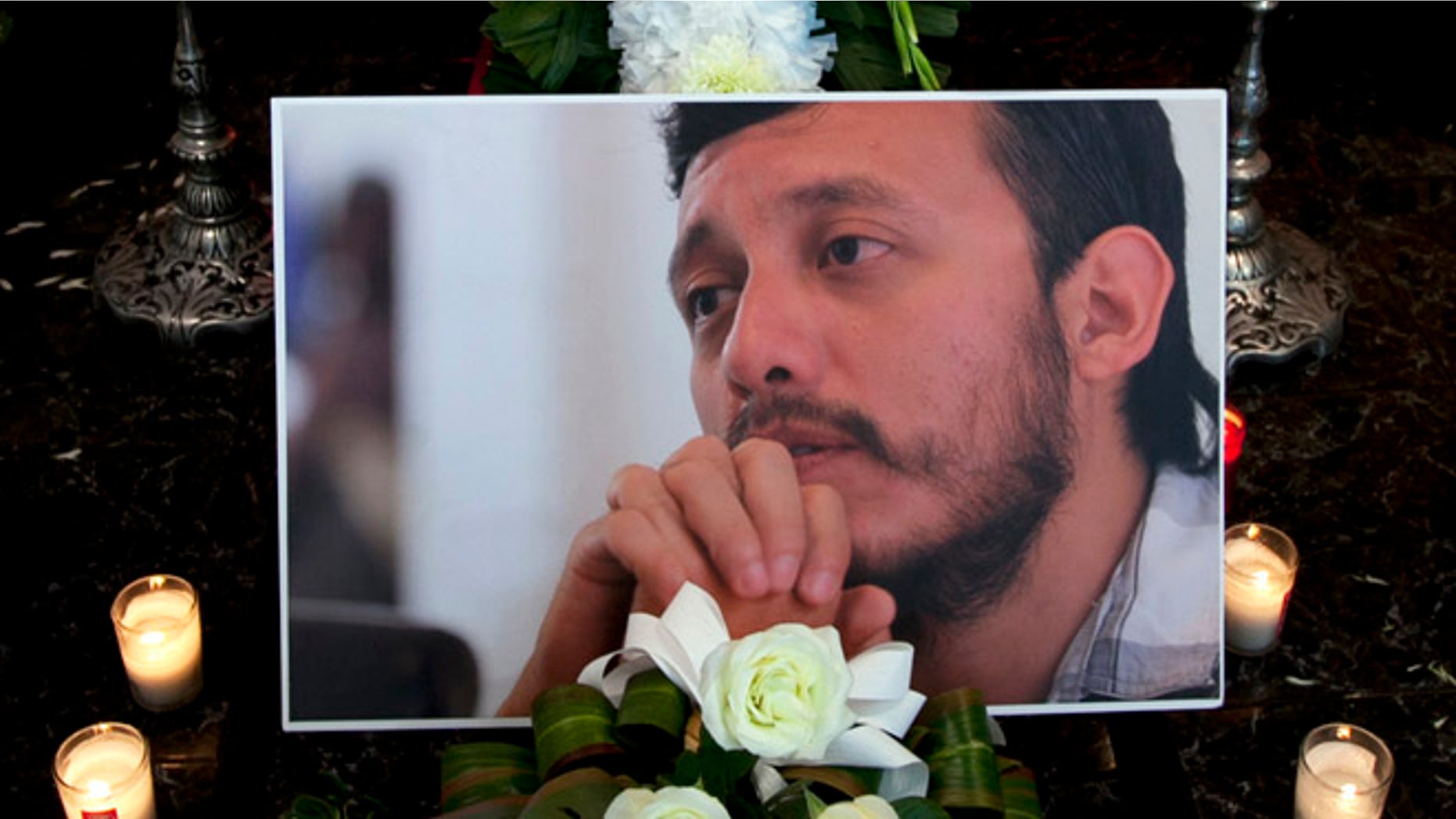 A photograph of murdered photojournalist Ruben Espinosa sits among flowers and candles in front of his casket inside a funeral home before his wake begins in Mexico City, Monday, Aug. 3, 2015.