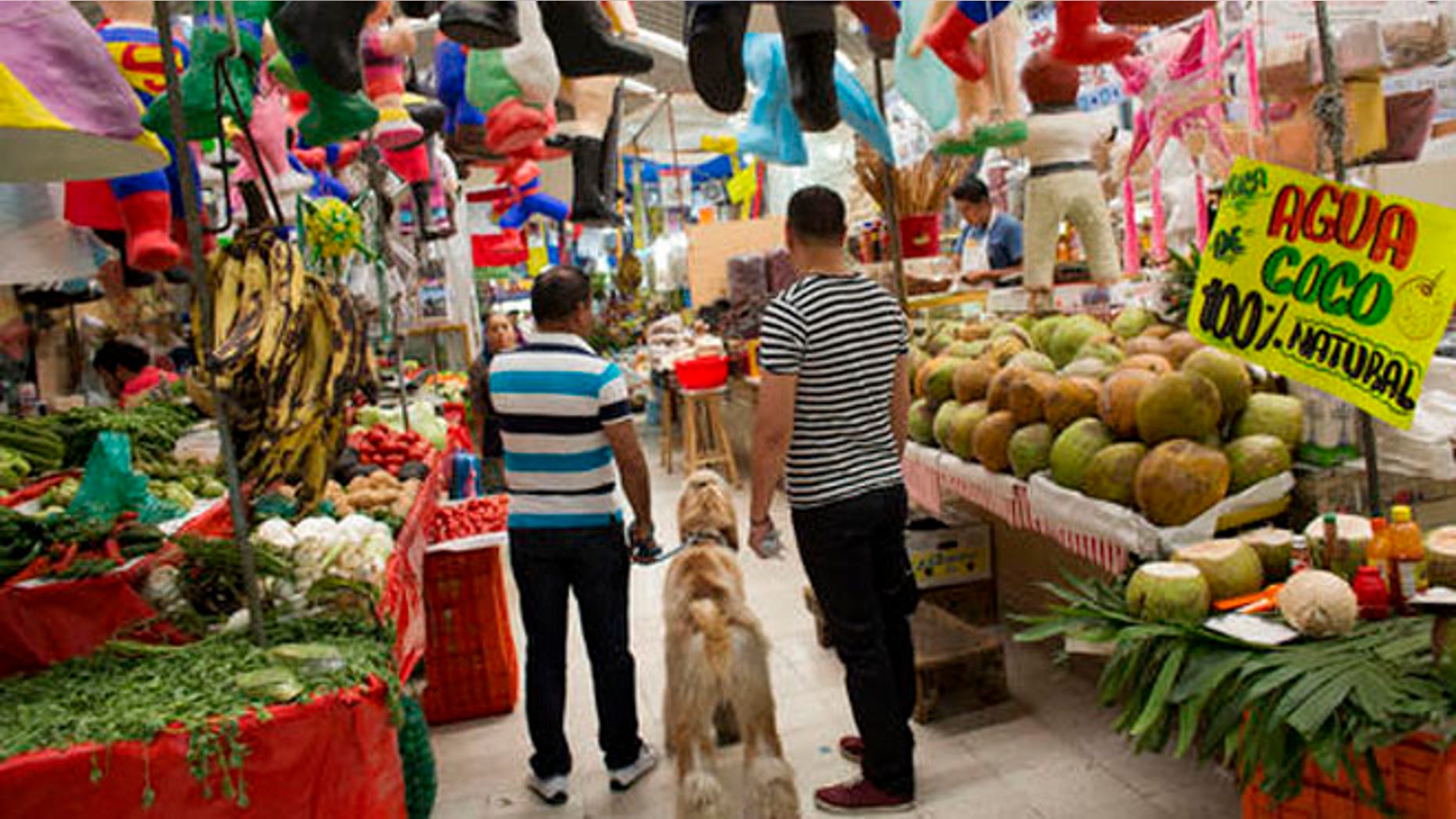 Men shop along with their dog inside Mercado Medellin in Mexico City, Friday, May 20, 2016. Mexico is lowering its economic growth forecast for 2016, citing what it calls "adverse" international conditions including sluggish industrial production in the United States. (AP Photo/Rebecca Blackwell)