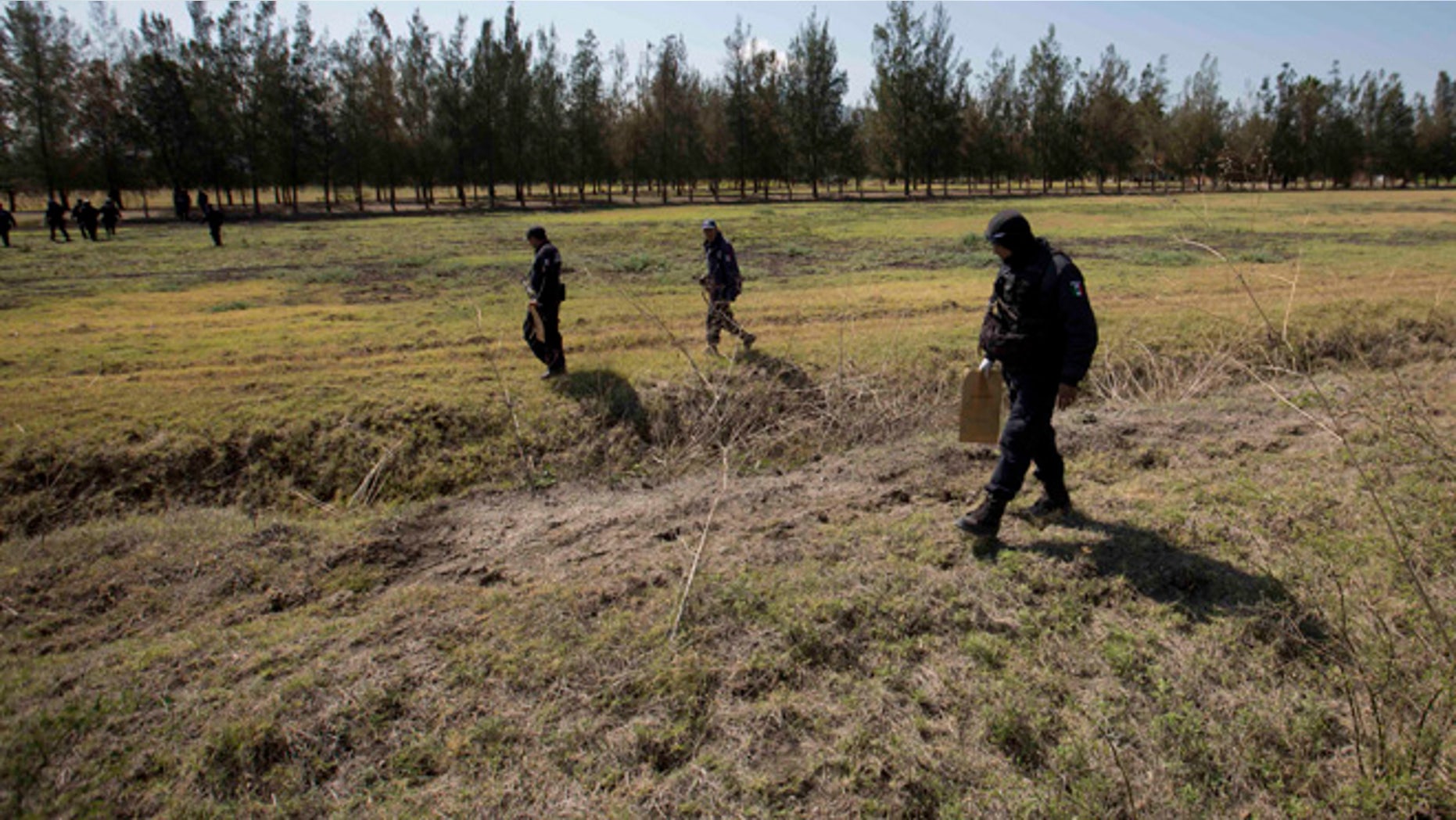 Police comb a field for evidence in the Rancho del Sol, a ranch in the municipality of Ecuandureo, Mexico, Saturday, May 23, 2015. The latest in a series of clashes between Mexican authorities and a powerful, fast-growing drug cartel turned into the deadliest confrontation in recent memory, with 42 suspected gang gunmen and one Federal Police officer killed on Friday during a three-hour firefight at this remote western ranch. (AP Photo/Eduardo Verdugo)