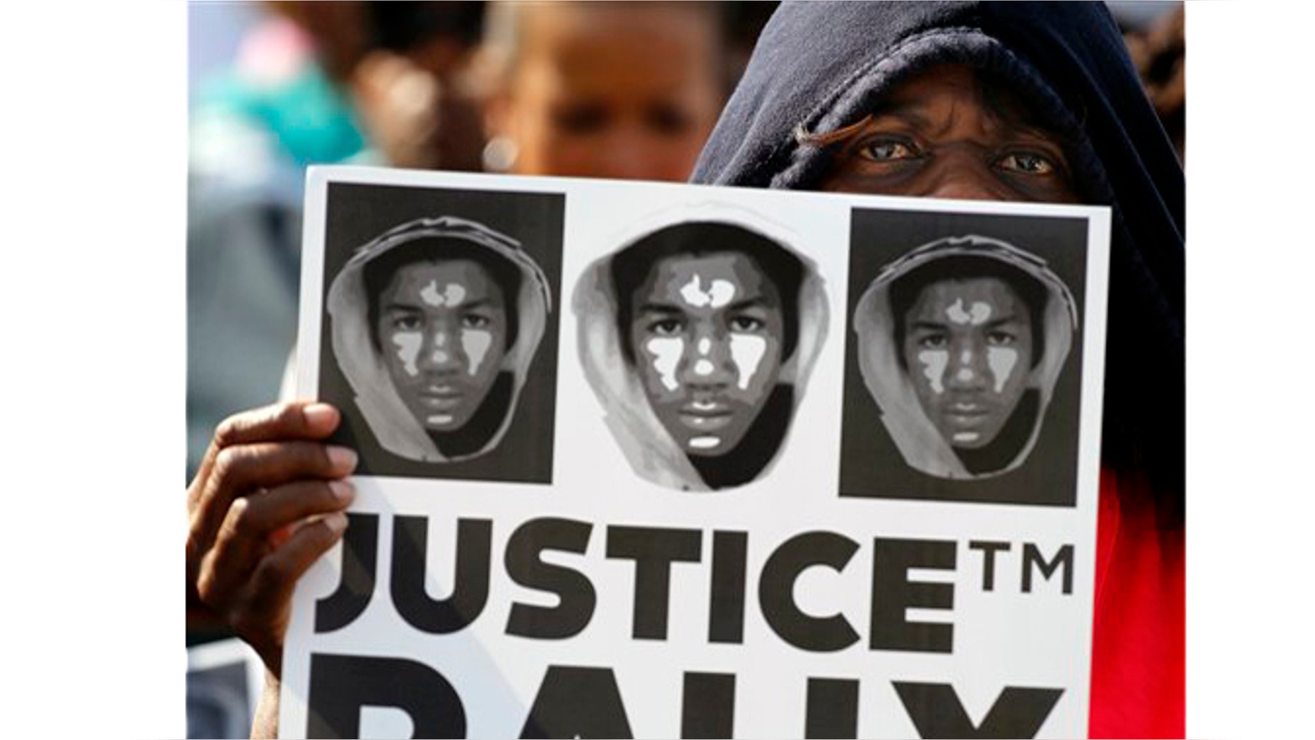 Arleen Poitier wears a hoodie and holds a protest sign as thousands gathered in downtown Miami, Sunday, April 1, 2012, demanding justice for Trayvon Martin, 17, who was fatally shot by a neighborhood watch member. Protesters say they will continue holding marches and rallies until the shooter, George Zimmerman, is arrested.