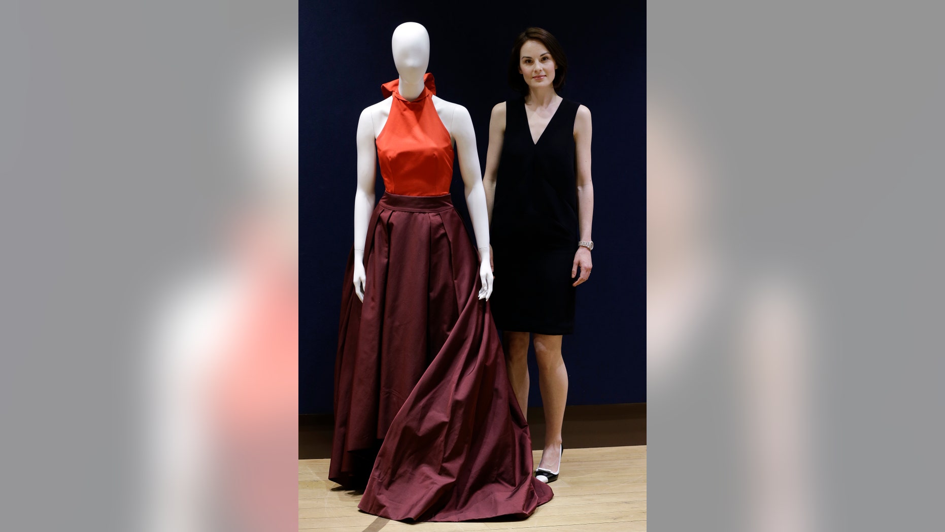 May 14, 2014. British actress Michelle Dockery, stands with her Prada gown that she wore to the 2013 Emmys at Christie's auction rooms in London."Downton Abbey" star Michelle Dockery is selling the eye-catching gown she wore to last year's Emmy Awards to help victims of the Syria civil war.
