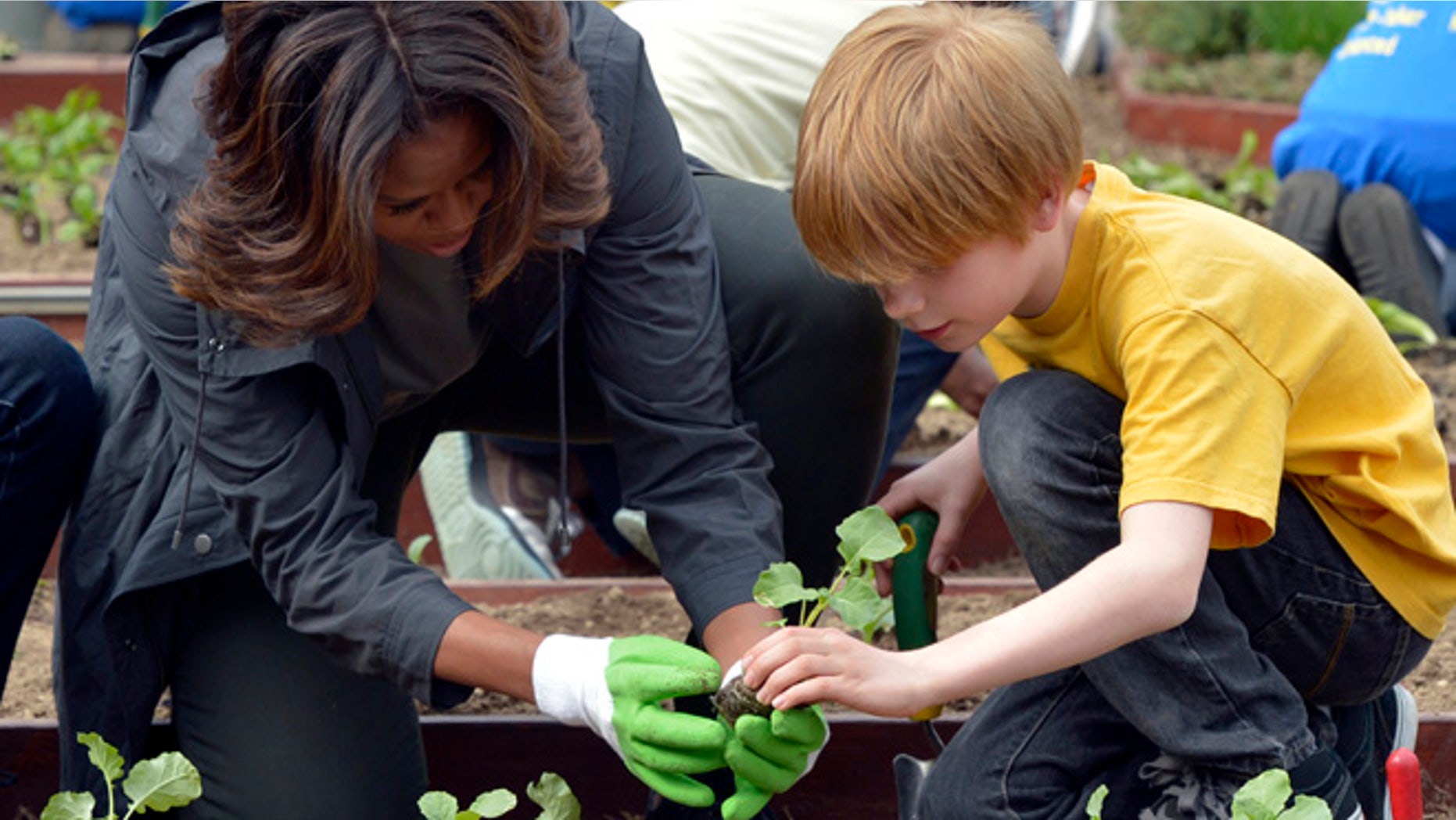 April 2, 2014: First lady Michelle Obama and Bancroft Elementary School student Silas Stutz plant broccoli in the White House Kitchen Garden in Washington.