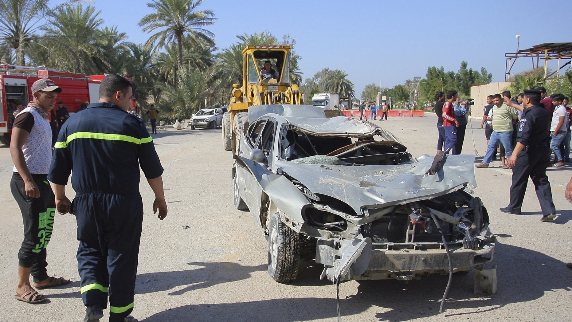 Civilians and security forces gather as municipality workers remove destroyed vehicles at the scene of a suicide bomb attack.
