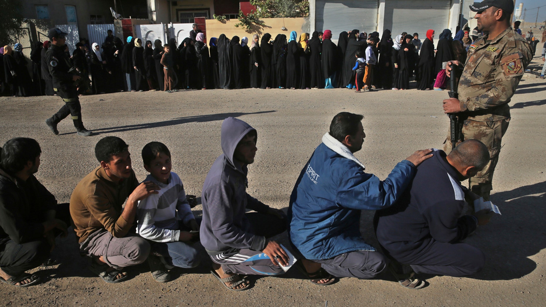 Iraqi citizens que to receive food supplies, at al-Arbajiyeh neighborhood, in Mosul, Iraq, Saturday, Nov. 19, 2016.