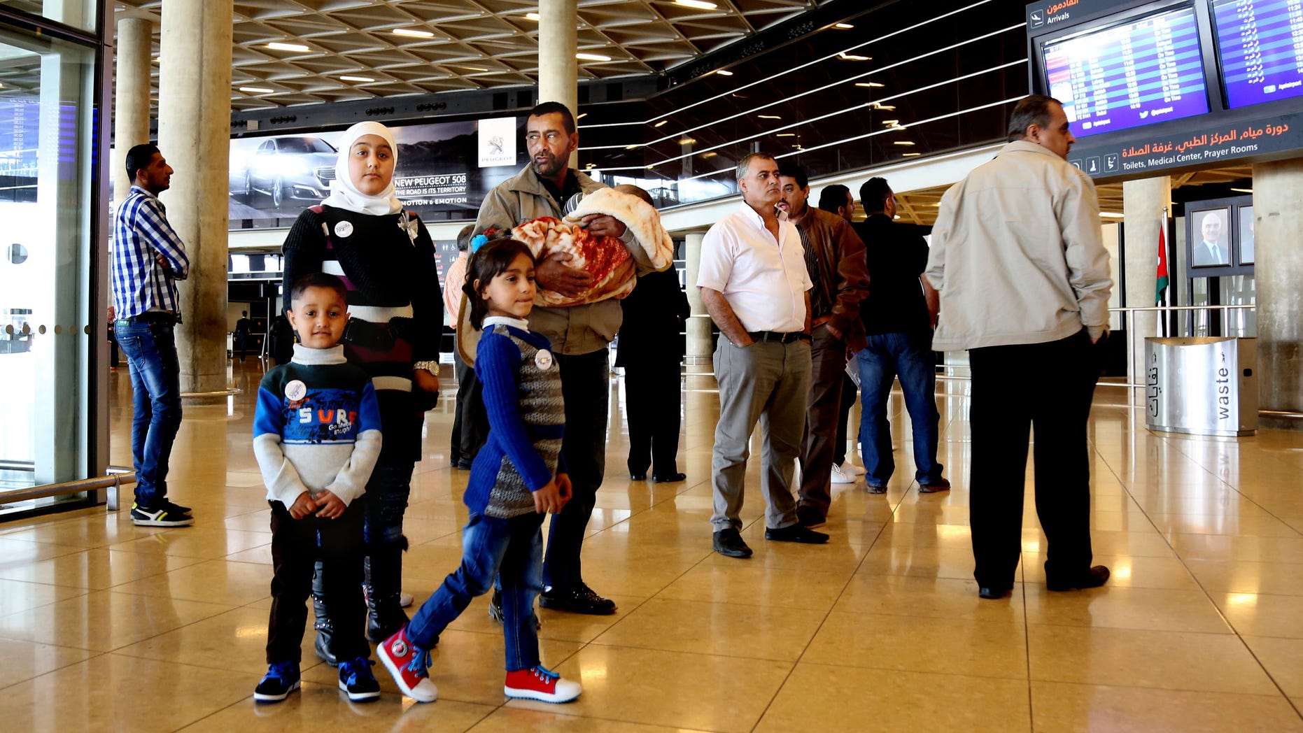 Syrian refugee Ahmad al-Abboud, center, waits with his family at the International Airport of Amman.