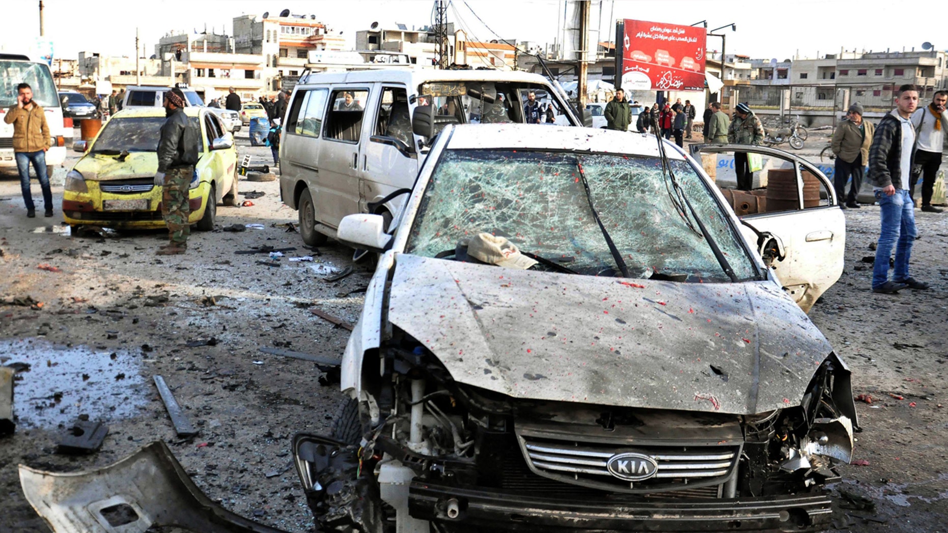 Jan. 26, 2016: In this photo released by the Syrian official news agency SANA, Syrian citizens gather at the scene where twin bombs exploded at a government-run security checkpoint, at the neighborhood of Zahraa, in Homs province, Syria. (SANA via AP)