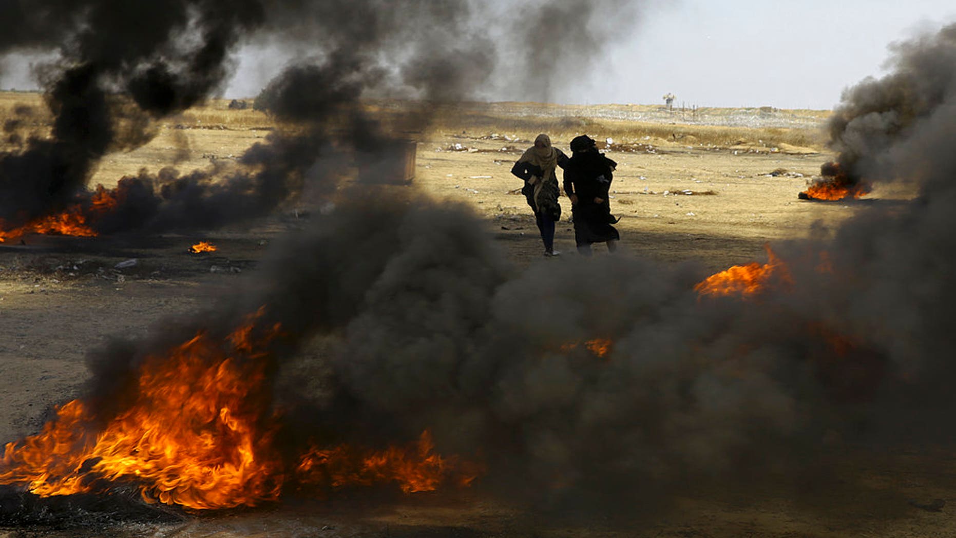 Palestinian women run for cover near the Gaza Strip's border with Israel, east of Khan Younis, in the Gaza Strip, Monday, May 14, 2018. Israeli fire has killed dozens of Palestinians during mass protests along the Gaza border, marking the deadliest day of violence since a devastating 2014 cross-border war and casting a pall over Israel's festive inauguration of the new U.S. Embassy in contested Jerusalem. (AP Photo/Adel Hana)