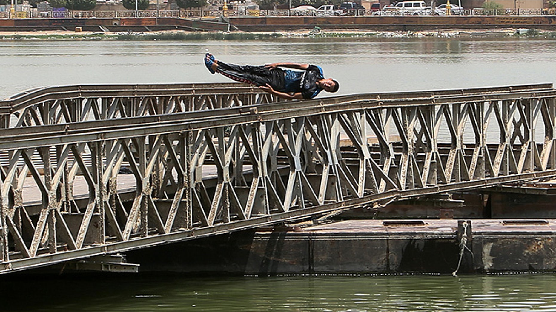 A man dives into the Shat al-Arab river in Basra Iraq. An unprecedented heat wave prompted Iraqi authorities to declare a mandatory four-day holiday beginning Thursday. The government has urged residents to stay out of the sun and drink plenty of water. (AP Photo/ Nabil al-Jurani)