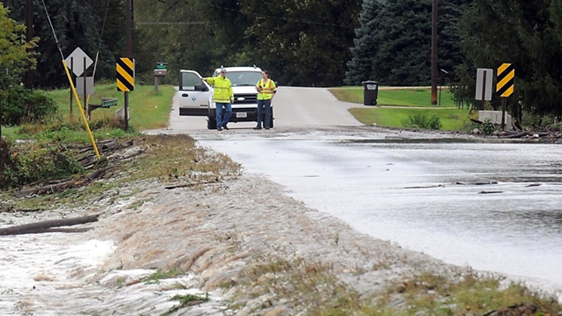 City of Mankato workers watch water flow over Indian Lake Road near Mount Kato Ski Area Thursday, Sept. 22, 2016 in Mankato, Minn. Overnight heavy rains caused flooding and mudslides. (Pat Christman/The Free Press via AP)